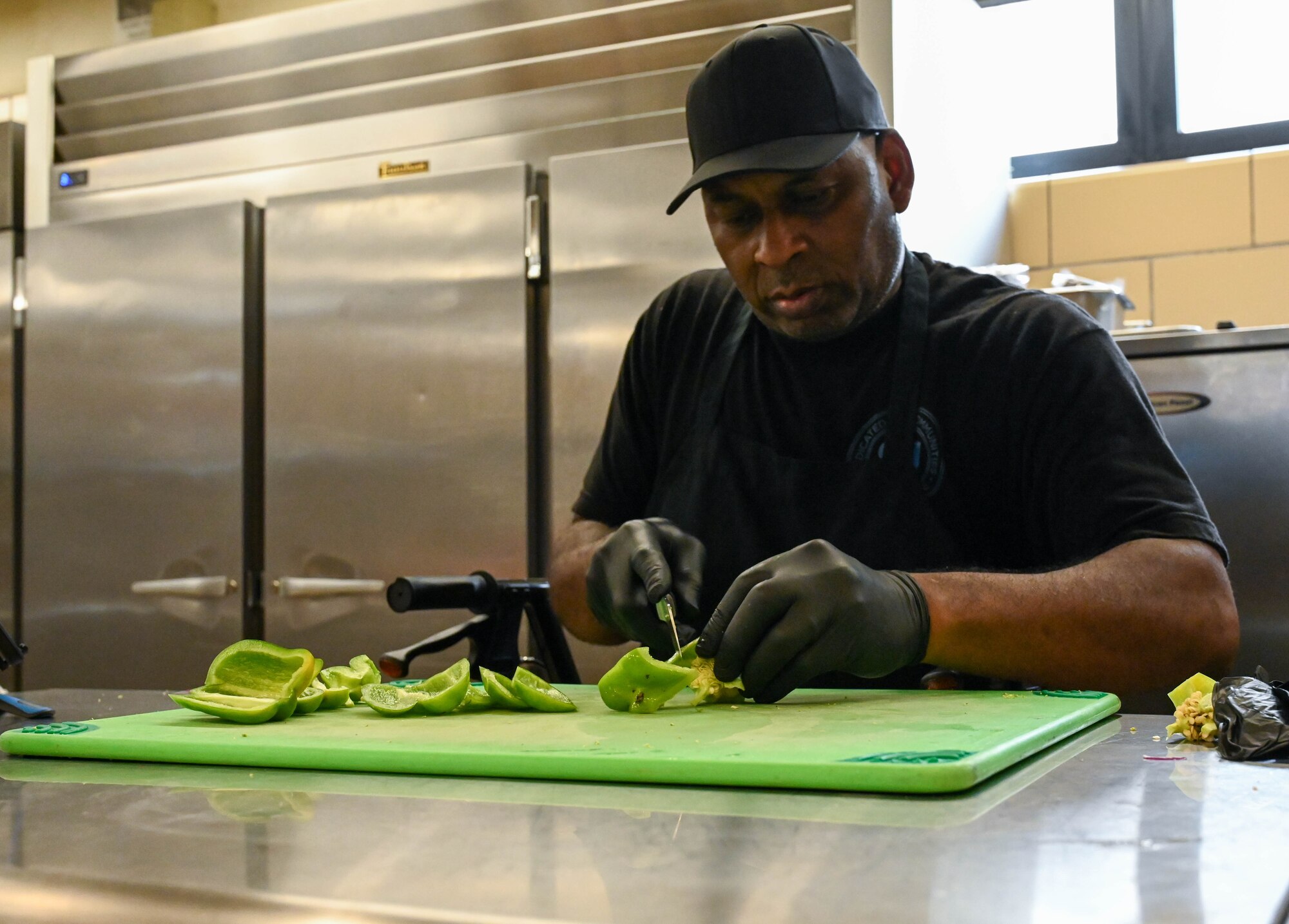 Patrick Willis, cook, cuts a bell pepper at Altus Air Force Base, Oklahoma, Sept. 5, 2024. Willis prepped fruits and vegetables to restock the salad bar at the Hangar 97 dining facility. (U.S. Air Force photo by Airman 1st Class Heidi Bucins)
