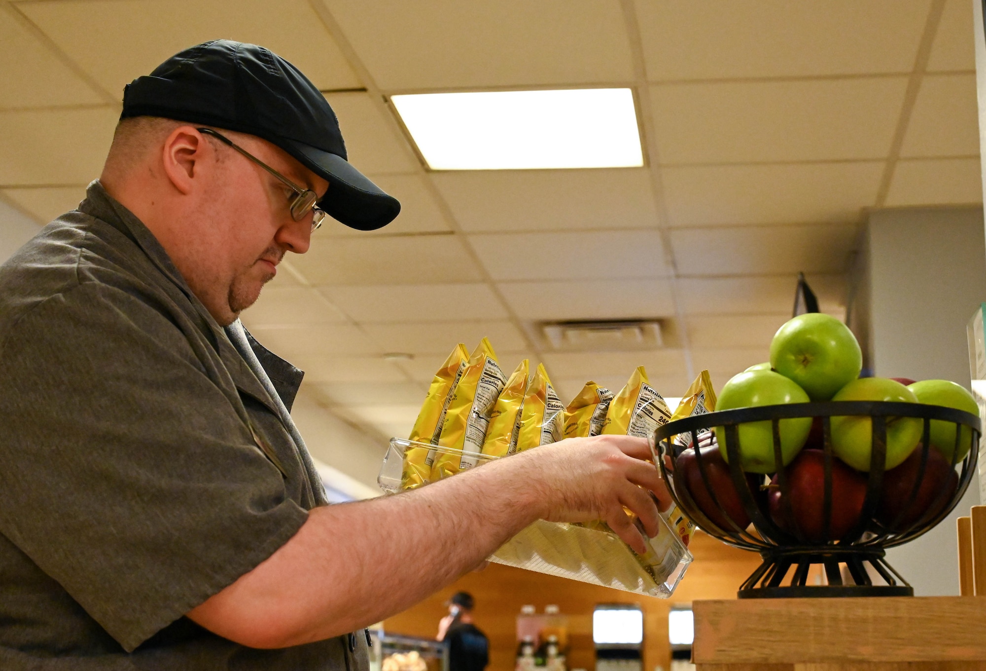 Steven Cantly, cashier, performs a quality assurance check at Altus Air Force Base, Oklahoma, Sept. 5, 2024. Cantly explained the importance of ensuring expiration standards are upheld at the Hangar 97 dining facility. (U.S. Air Force photo by Airman 1st Class Heidi Bucins)