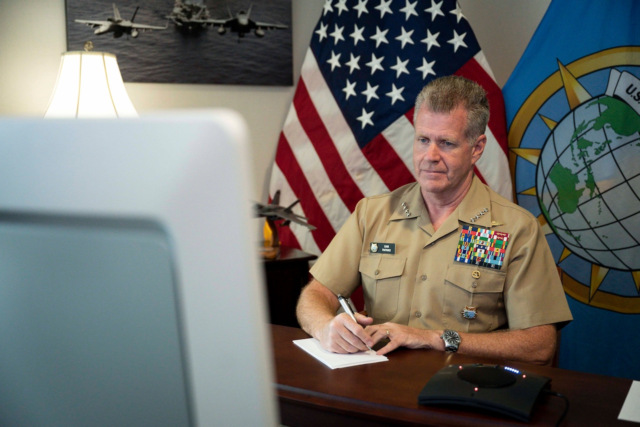 A service member in uniform sits at a desk.