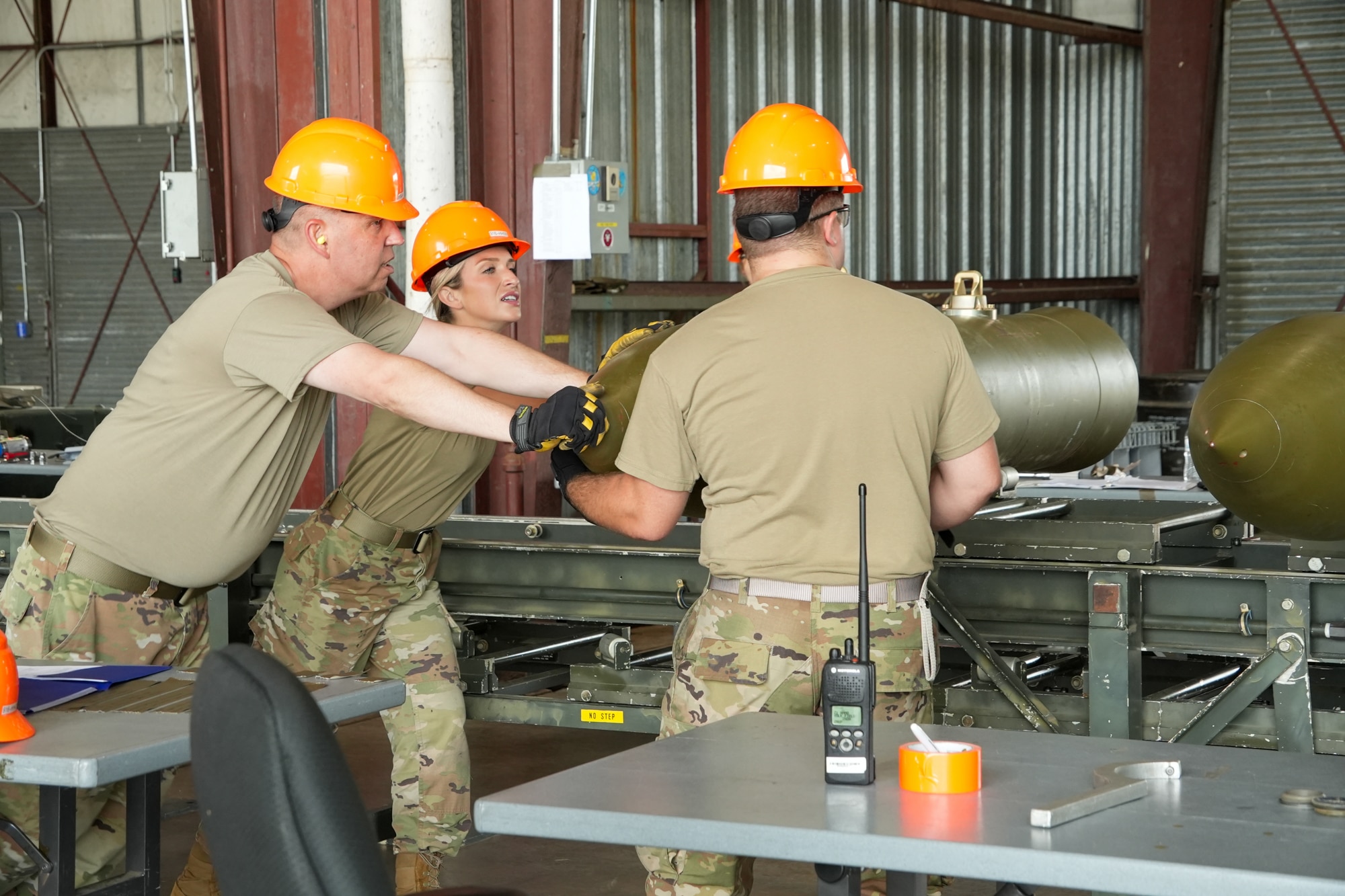 Air Force members work together to manually move a bomb body into position for assembly.