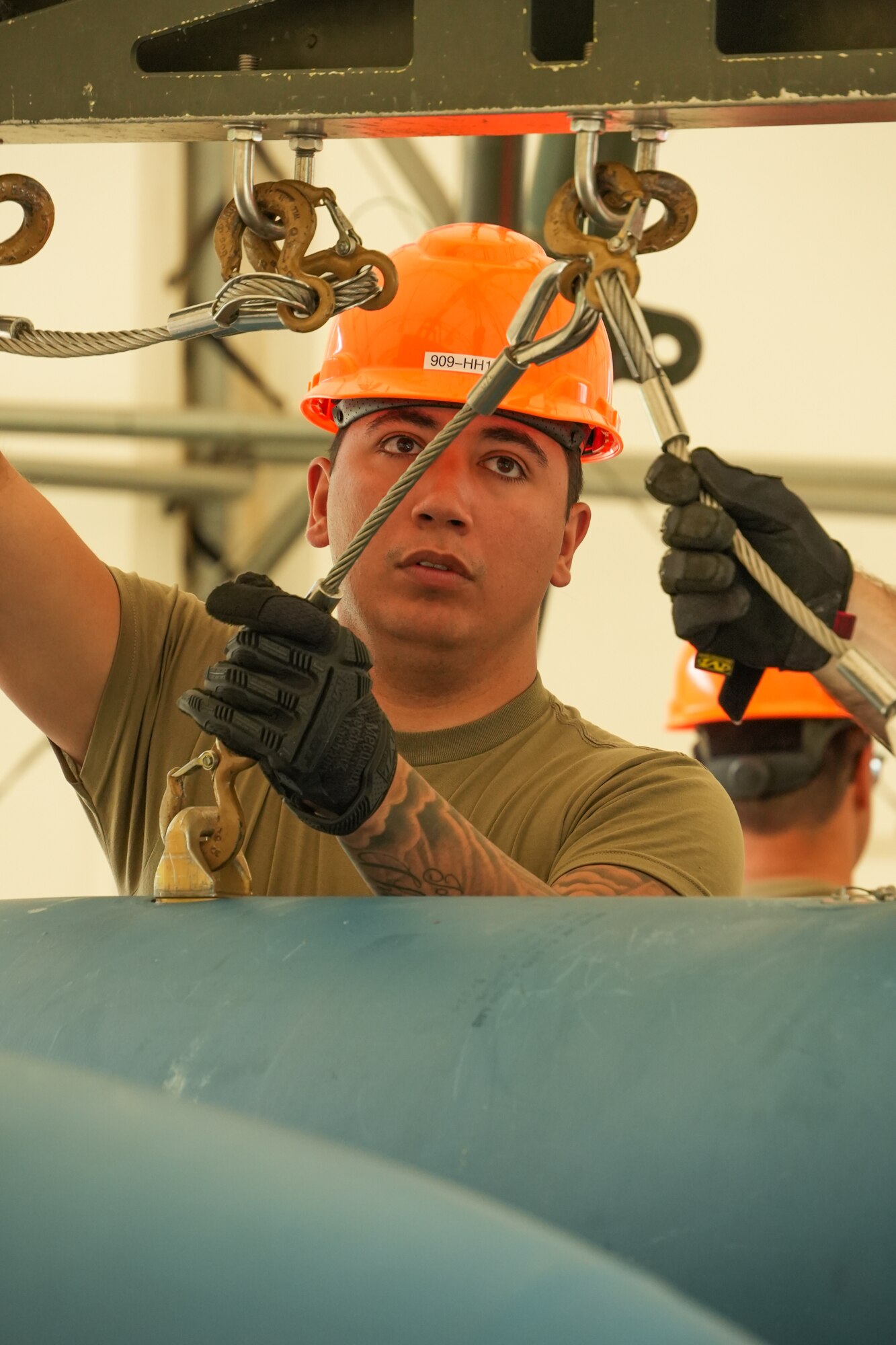 Air Force member attaches slings to a 2,000-lb general purpose heavy unguided bomb body.