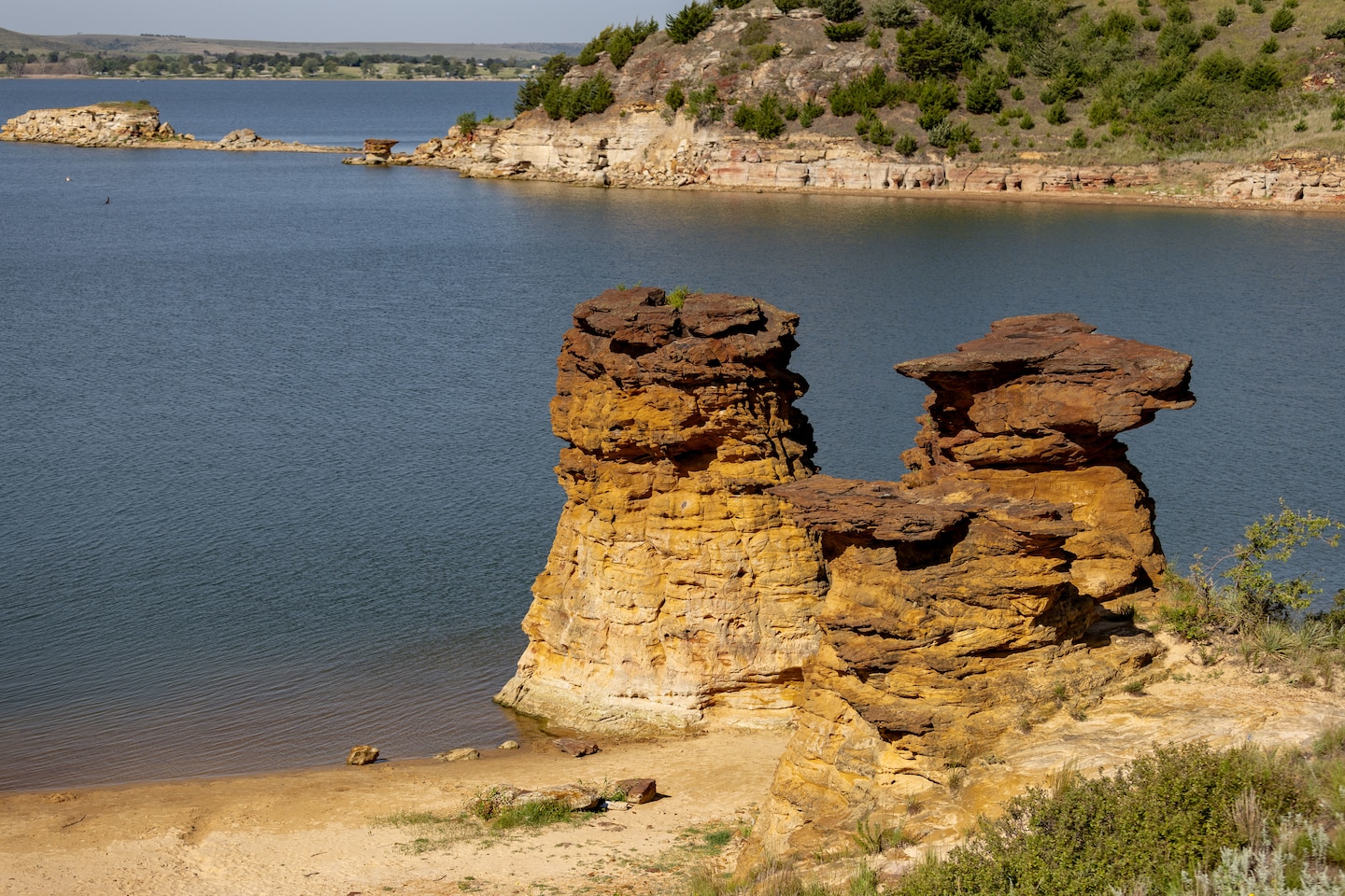 A rock formation is in the foreground with water and grass in the background.