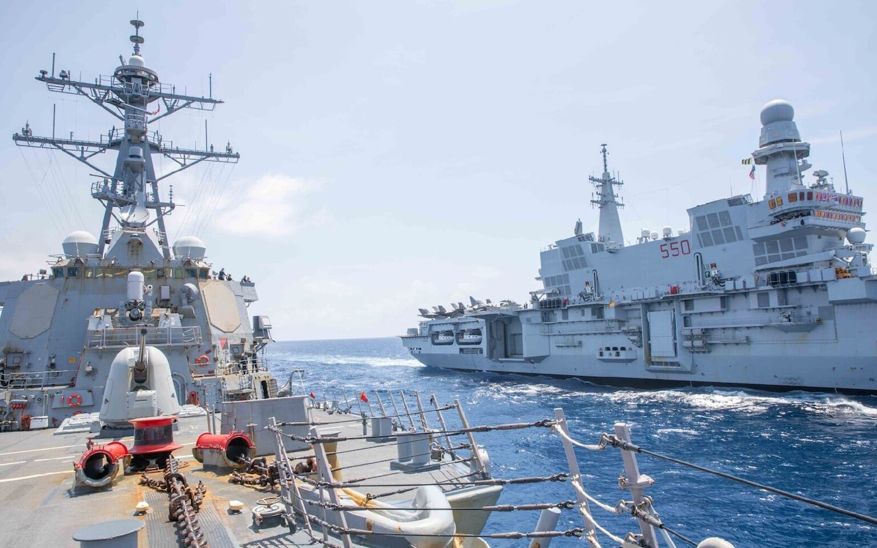 Two large warships sail alongside each other in the ocean.