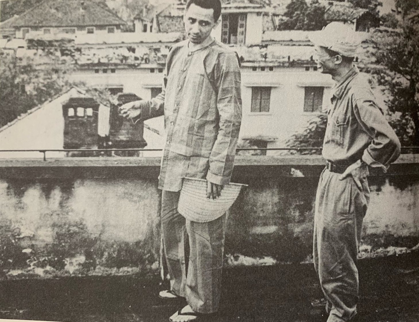 Lt. j.g. Everett Alvarez, Jr., in his striped prison uniform, talks with a Vietnamese prison guard while in downtown Hanoi, North Vietnam, ca. 1967. Vietnamese prison guards routinely escorted American POWs around town to view nationalist- and Communist-themed museum exhibits and other landmarks. They were often paraded before crowds of angry Vietnamese townspeople and photographed for propaganda purposes (Office of the Secretary of Defense).