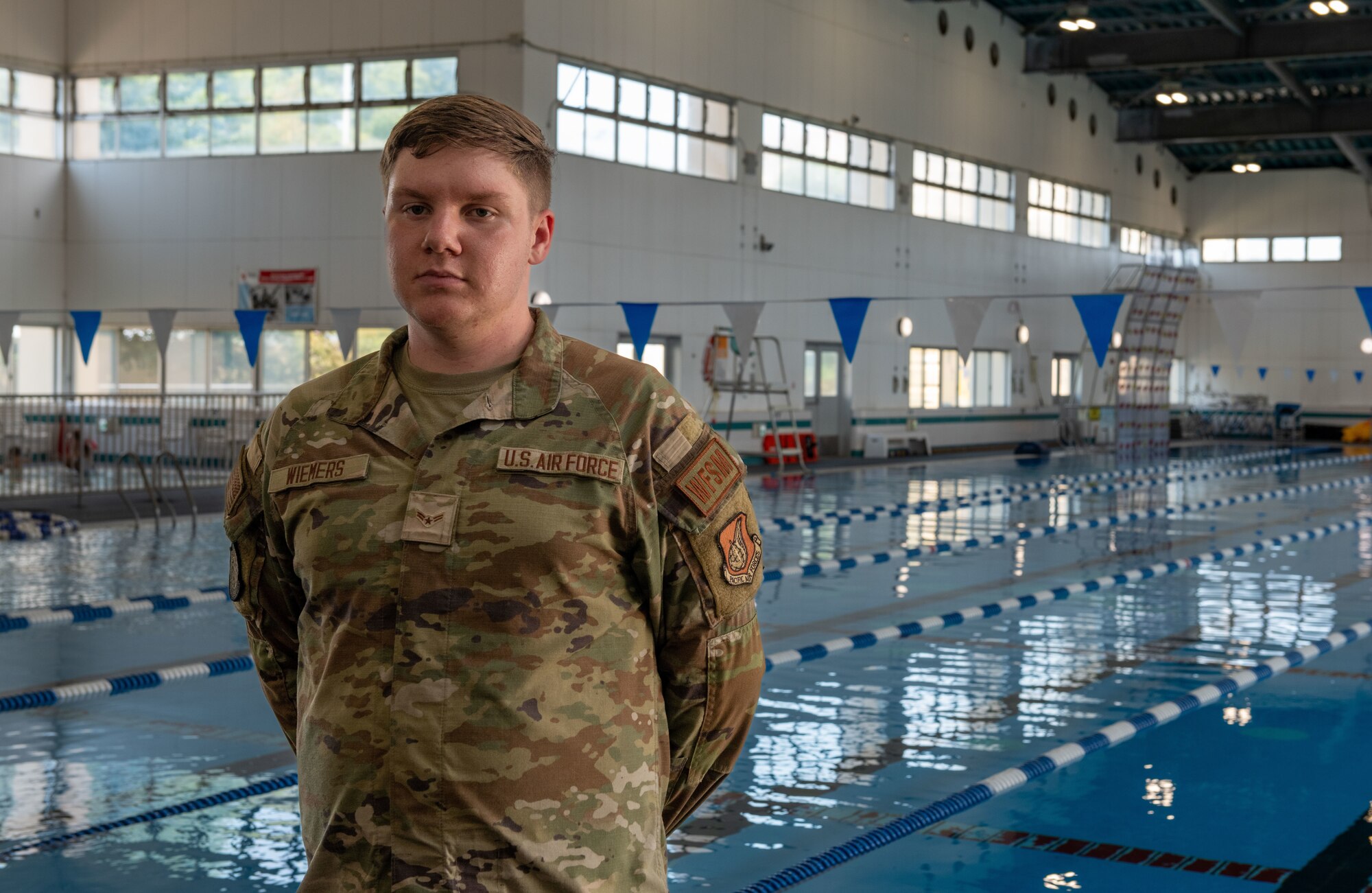 An airman assigned to the 374th Civil Engineer Squadron poses for a photo in front of a pool.