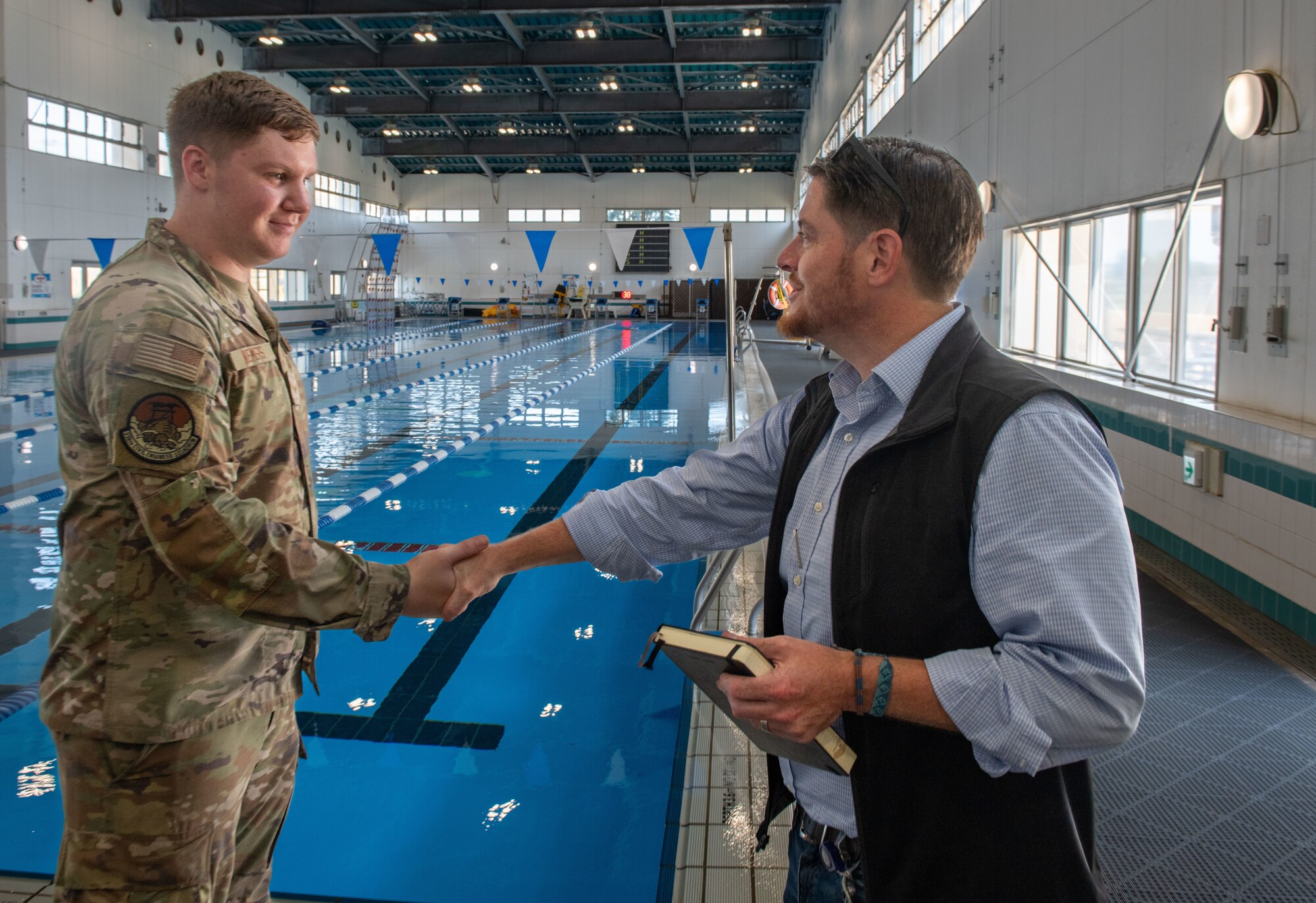 Honorable Brendan Owens coins and airman in front of a pool
