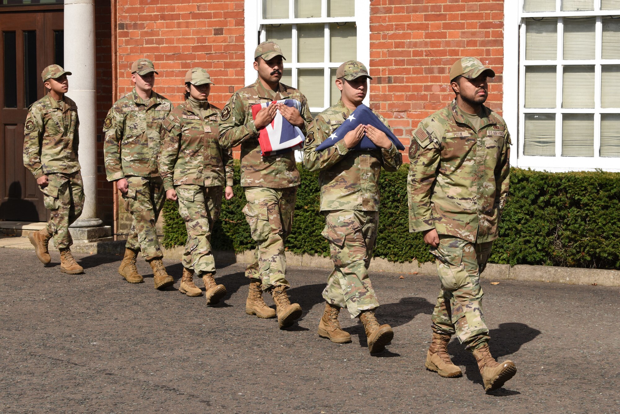 U.S. Airmen from the Team Mildenhall Honor Guard march off with the folded Stars and Stripes and Royal Air Force Ensign flags during a retreat ceremony concluding POW/MIA Week at Royal Air Force Mildenhall, England, Sept. 13, 2024. The week remembered and honored those Americans who were prisoners of war and those who served and never returned home. (U.S. Air Force photo by Karen Abeyasekere)