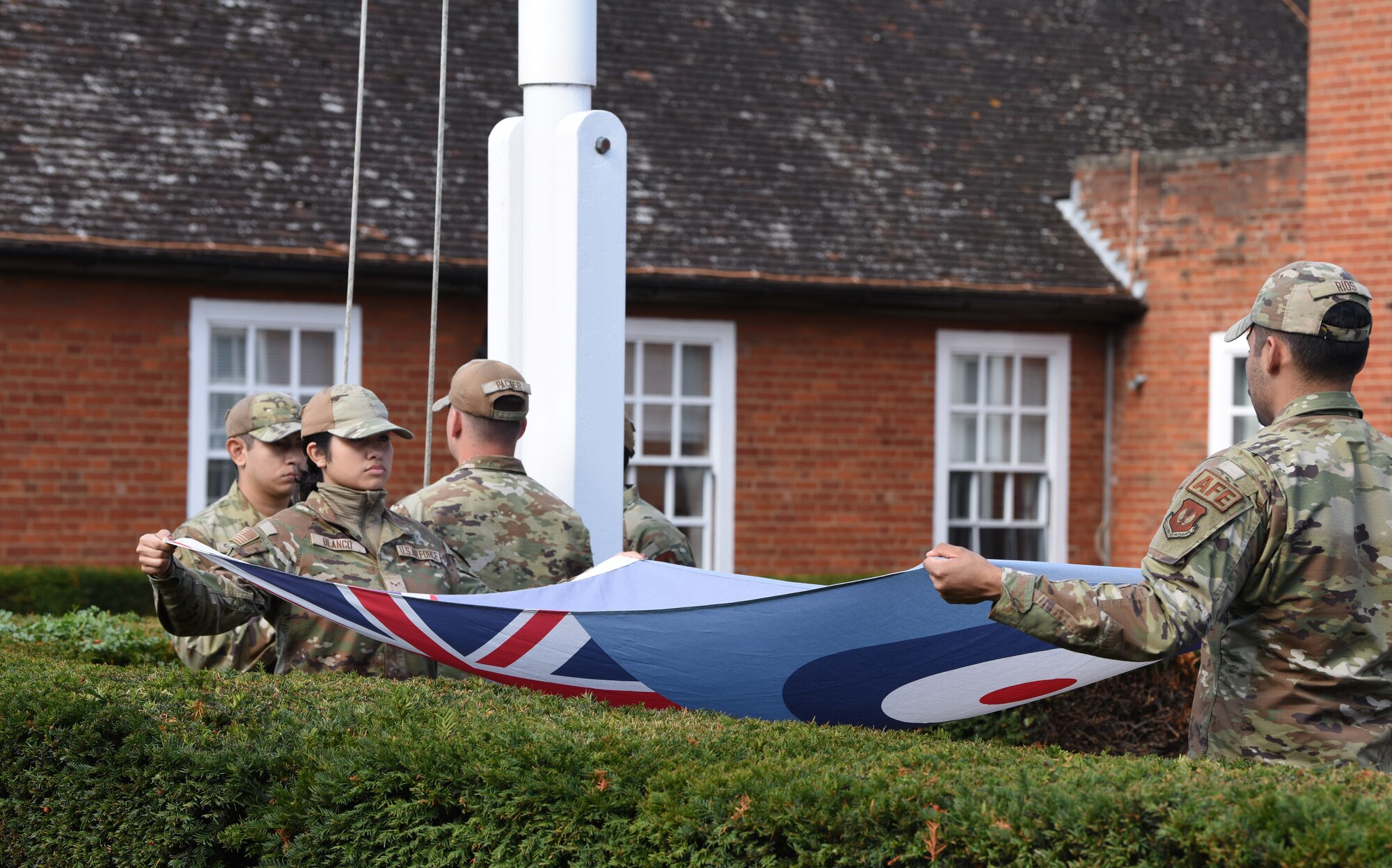 U.S. Airmen from the Team Mildenhall Honor Guard fold the Royal Air Force Ensign flag during a retreat ceremony concluding POW/MIA Week at Royal Air Force Mildenhall, England, Sept. 13, 2024. The week remembered and honored those Americans who were prisoners of war and those who served and never returned home. (U.S. Air Force photo by Karen Abeyasekere)