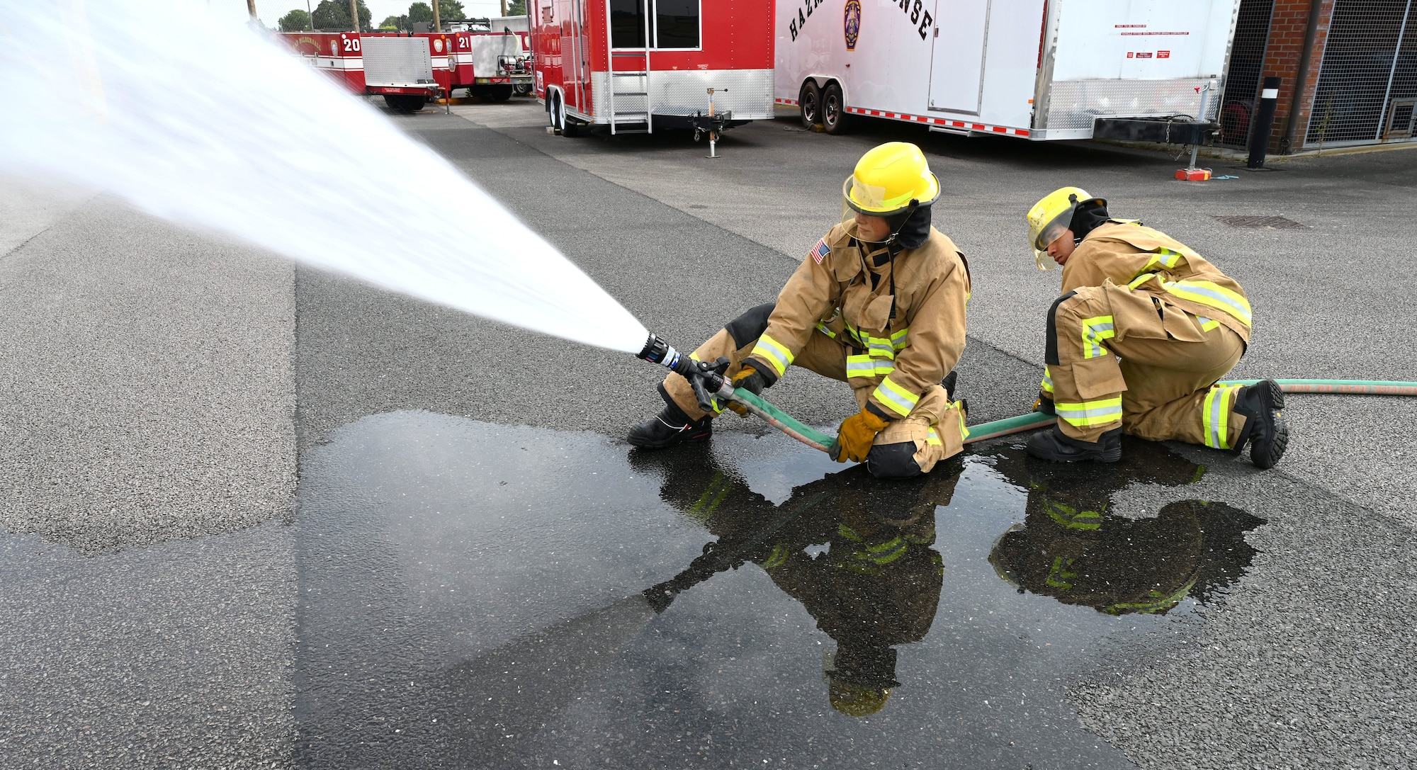 U.S. Air Force Airman Corban La Quey, left, and Airman Jeniel DeJesus, 100th Civil Engineer Squadron Fire Department firefighter rookies, practice fire hose techniques as part of their “Rookie Academy” training at Royal Air Force Mildenhall, England, Aug. 28, 2024. The Rookie Academy is an intense training program designed by Staff Sgt. Connor Nance, 100th CES Fire Department assistant chief of training, and taught by multiple experienced firefighters. It condenses four months of training for new firefighters into three weeks, ensuring they all learn the same way, so they receive a high-quality level of training while maintaining that consistency of training across the board. This in turn gives the rookies a head-start on completing their career-based training, putting them ahead of their peers at other bases. (U.S. Air Force photo by Karen Abeyasekere)