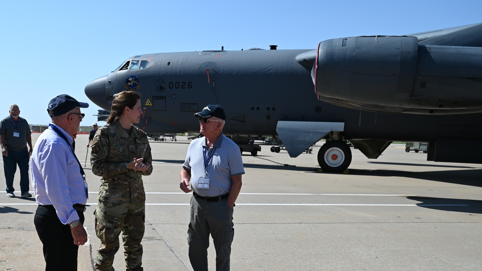 Two men talking to woman in front of aircraft.