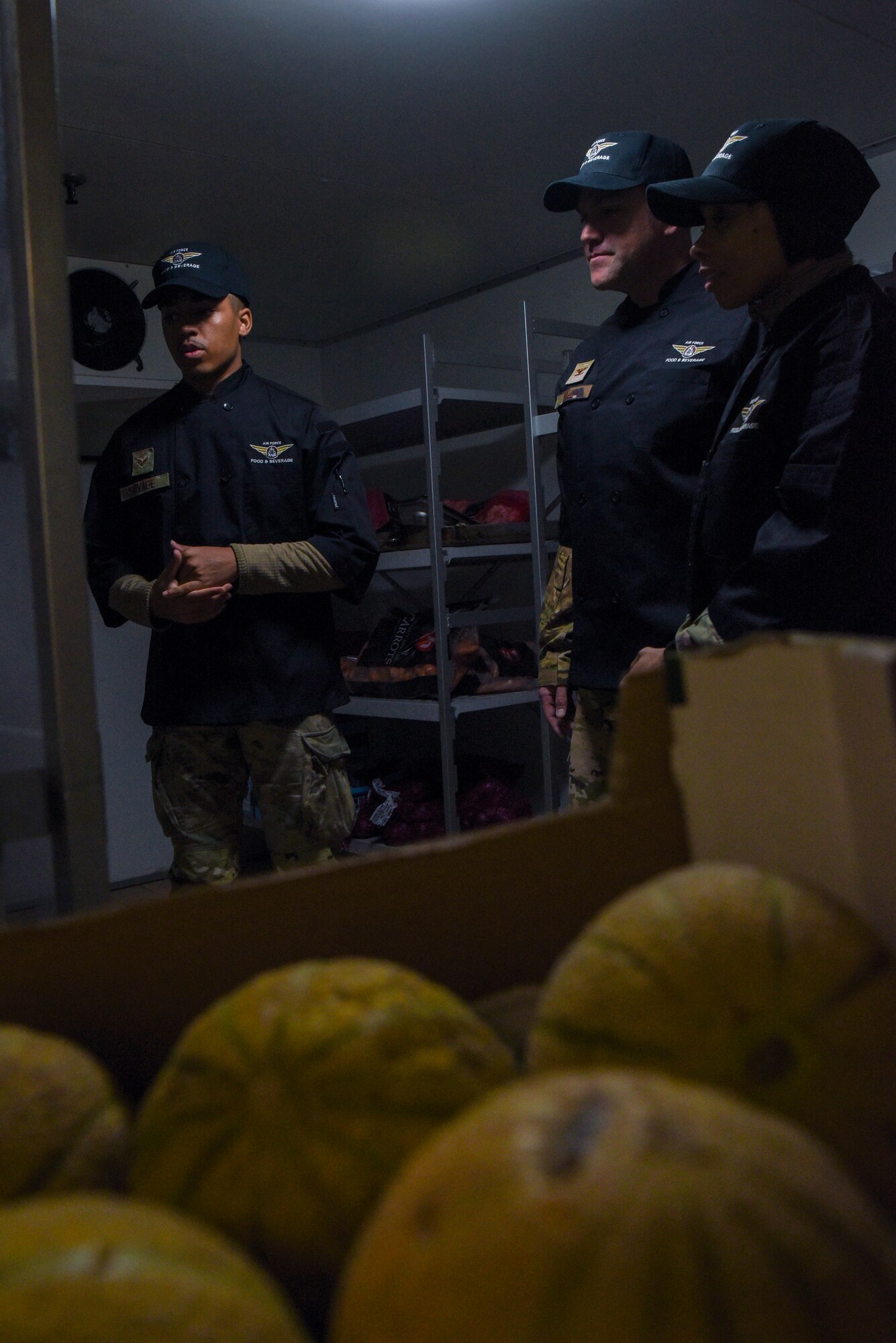 U.S. Air Force Senior Airman Jurell Savage, left, 100th Force Support Squadron Gateway Dining Facility storeroom manager, explains how the dining facility stocks and organizes food to Col. Joseph Wall, center, 100th Air Refueling Wing deputy commander, and Chief Master Tiffany Griego, 100th ARW command chief, during a “Day in the Life” immersion at Royal Air Force Mildenhall, England, Sept. 13, 2024.