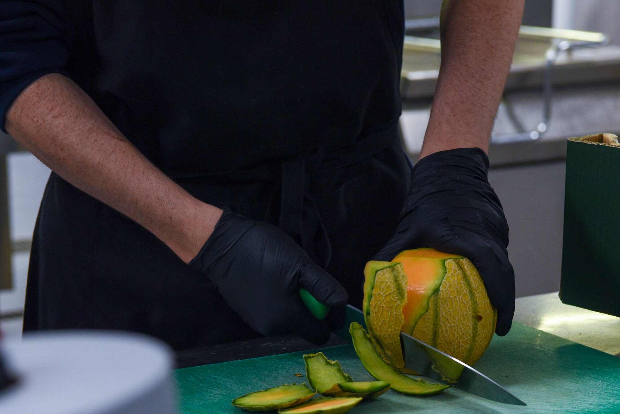 Cameron Goldie, 100th Force Support Squadron Gateway Dining Facility food service worker, demonstrates how to cut a cantaloupe during a “Day in the Life” immersion with the 100th Air Refueling Wing command team at Royal Air Force Mildenhall, England, Sept. 13, 2024.