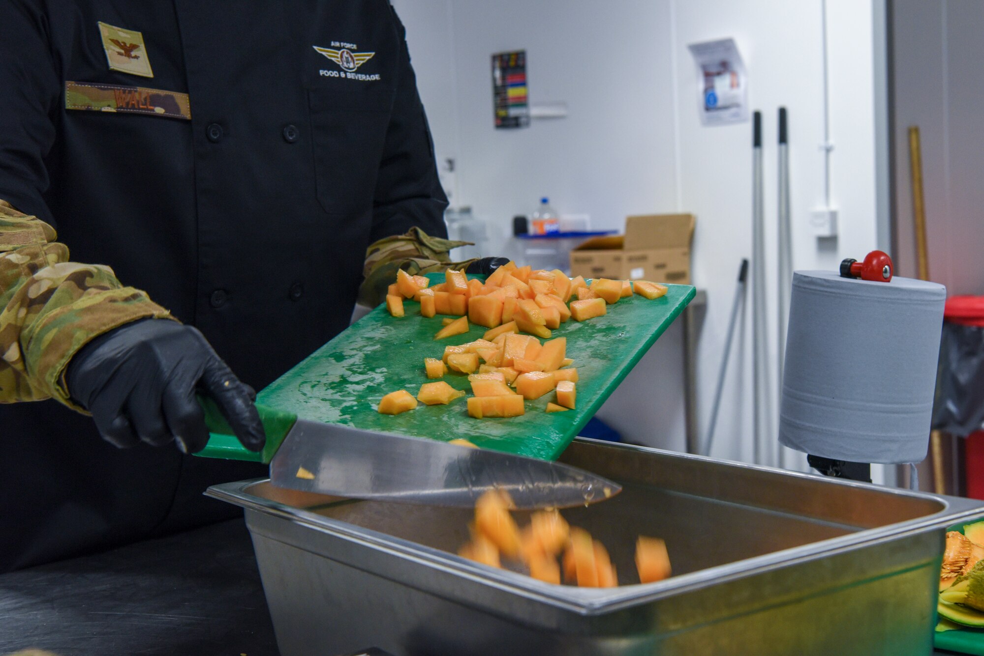 U.S. Air Force Col. Joseph Wall, 100th Air Refueling Wing deputy commander, pushes cut cantaloupe into a storage tray during a “Day in the Life” immersion with the 100th Force Support Squadron Gateway Dining Facility at Royal Air Force Mildenhall, England, Sept. 13, 2024.