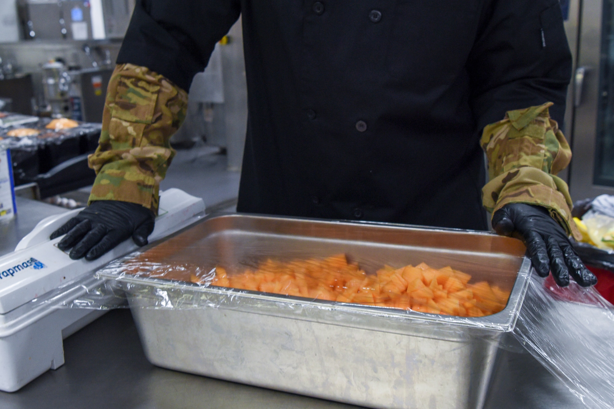 U.S. Air Force Col. Joseph Wall, 100th Air Refueling Wing deputy commander, covers cut cantaloupe during a “Day in the Life” immersion with the 100th Force Support Squadron Gateway Dining Facility at Royal Air Force Mildenhall, England, Sept. 13, 2024.
