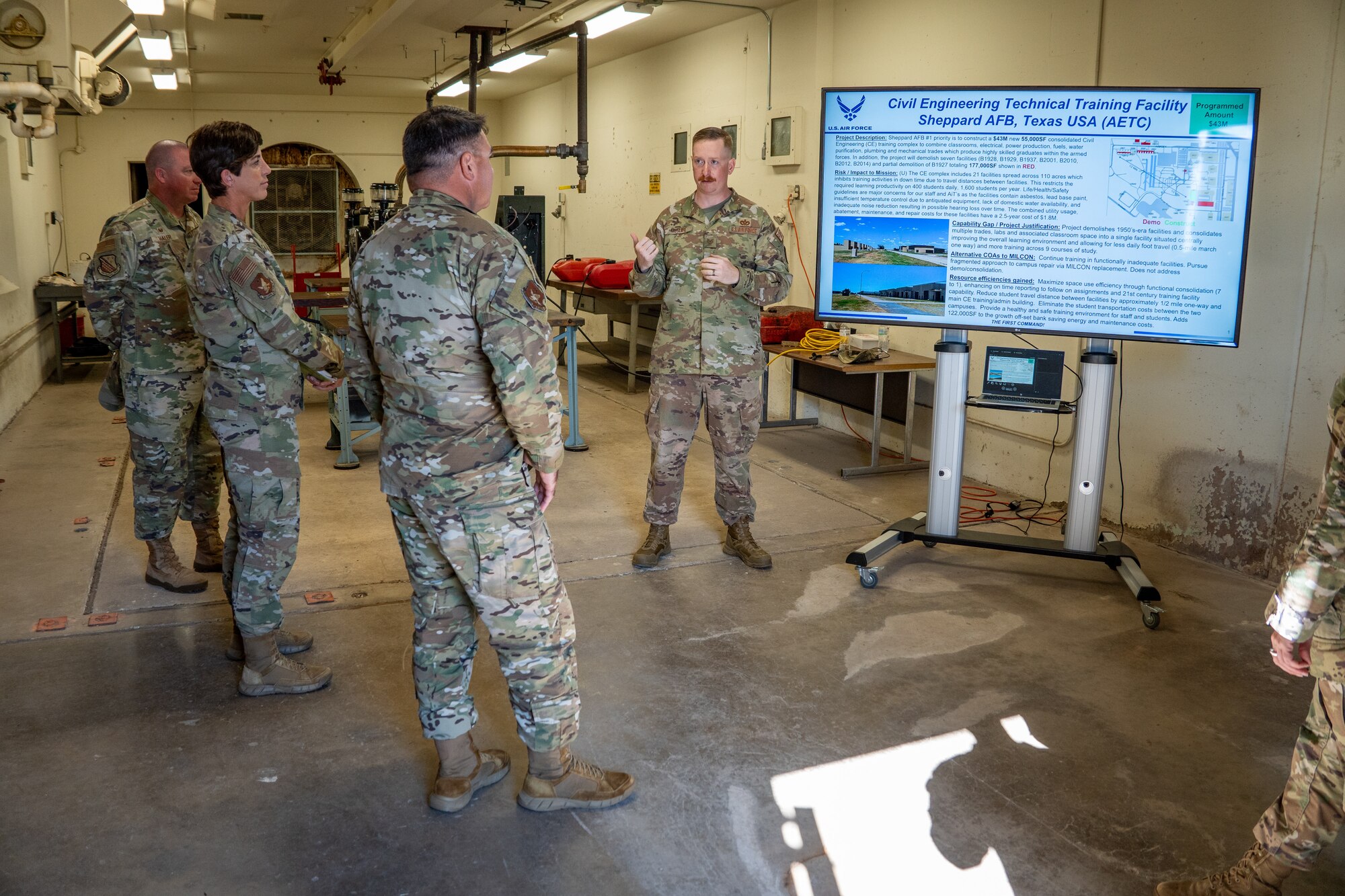 One Airman speaks to more Airman. They are looking at a monitor.