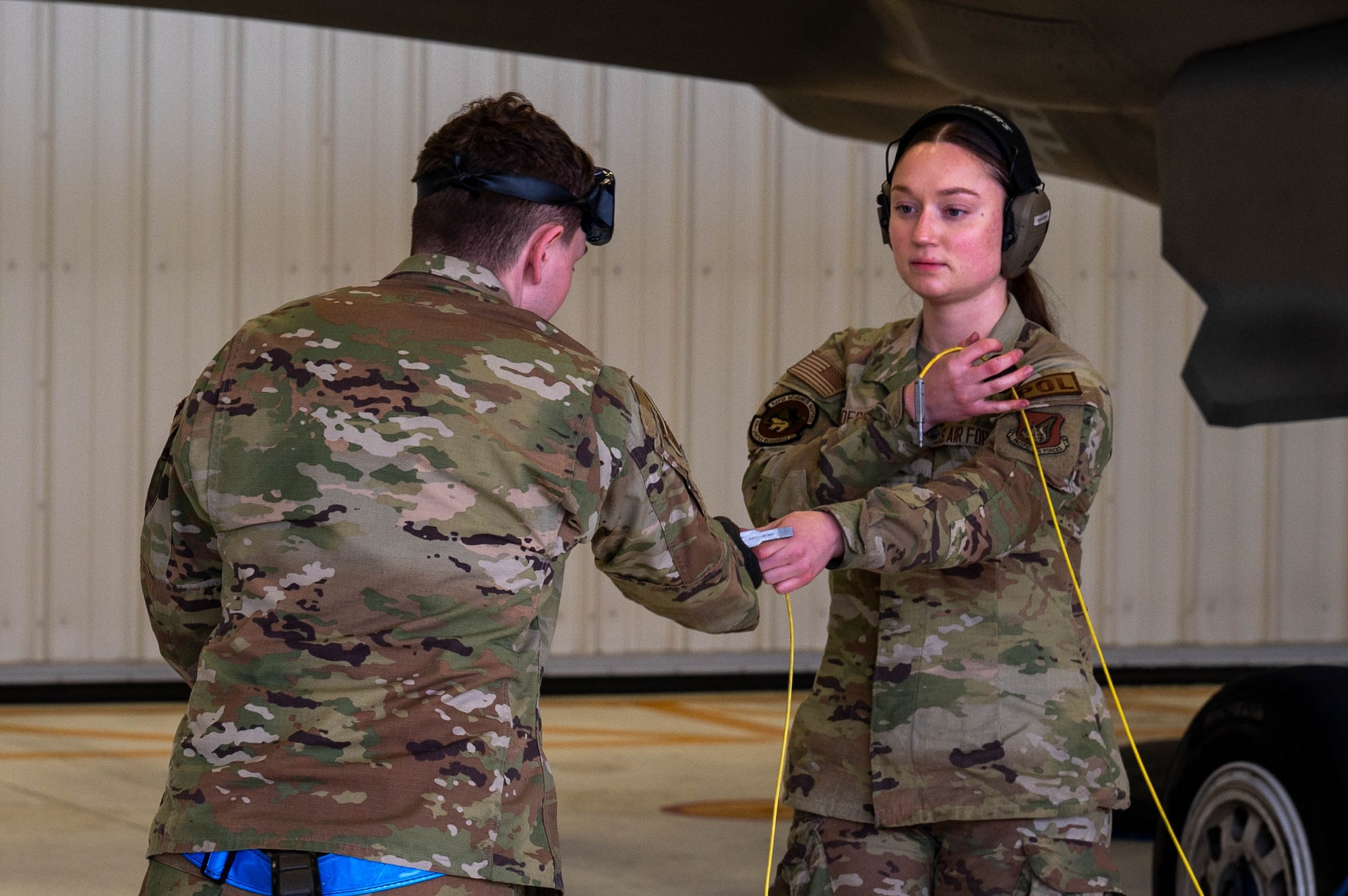 U.S. Air Force Airman Kaelin Sanders (right), 354th Logistics Readiness Squadron fuels operator, hands grounding cables to Senior Airman Richard Brown, 355th Fighter Generation Squadron assistant dedicated crew chief, before refueling an F-35A Lightning II at Eielson Air Force Base, Alaska, Sept. 12, 2024.