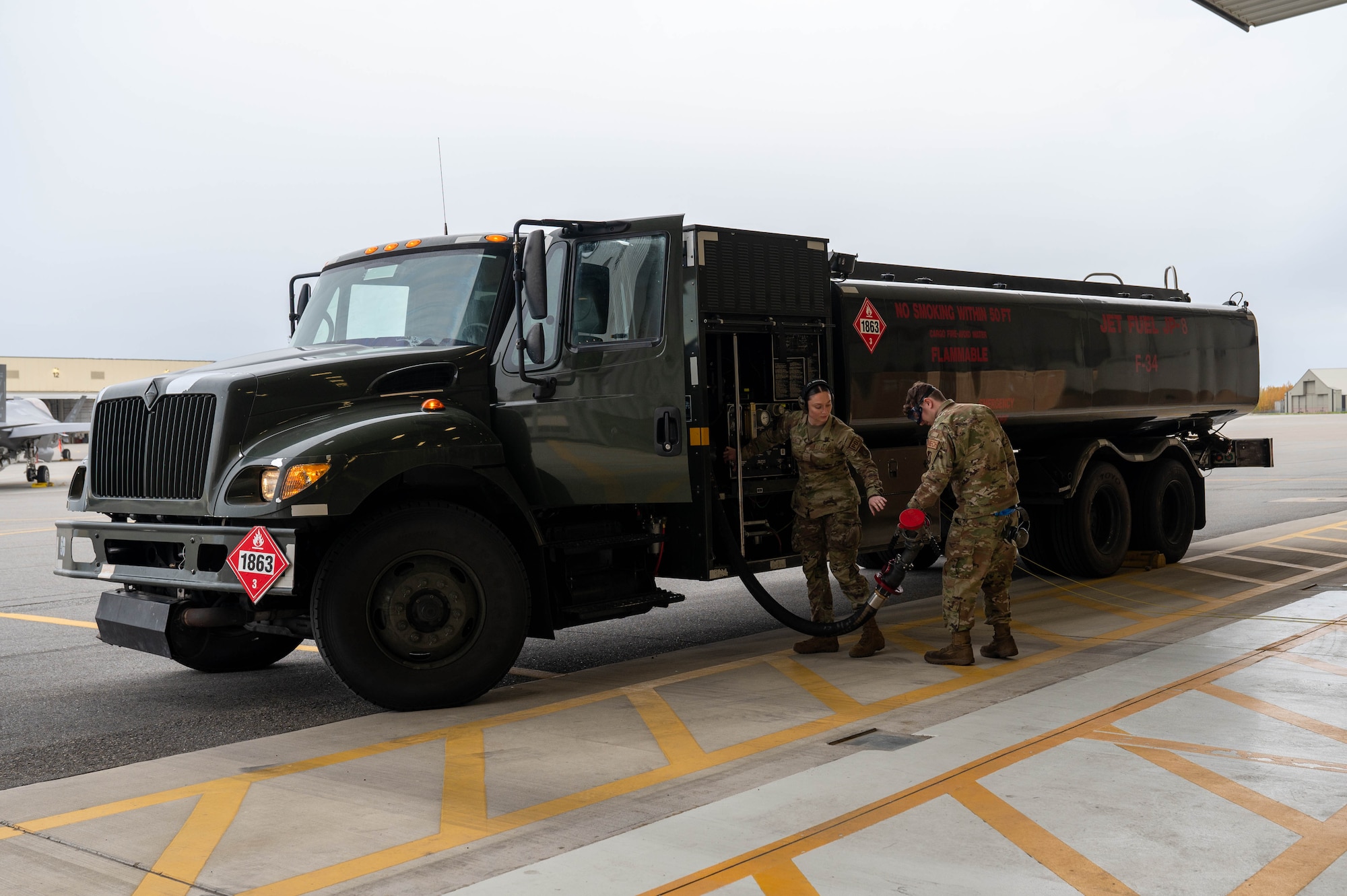 U.S. Air Force Airman Kaelin Sanders (left), 354th Logistics Readiness Squadron fuels operator, receives a fueling hose from Senior Airman Richard Brown, 355th Fighter Generation Squadron assistant dedicated crew chief, after refueling an aircraft at Eielson Air Force Base, Alaska, Sept. 12, 2024.