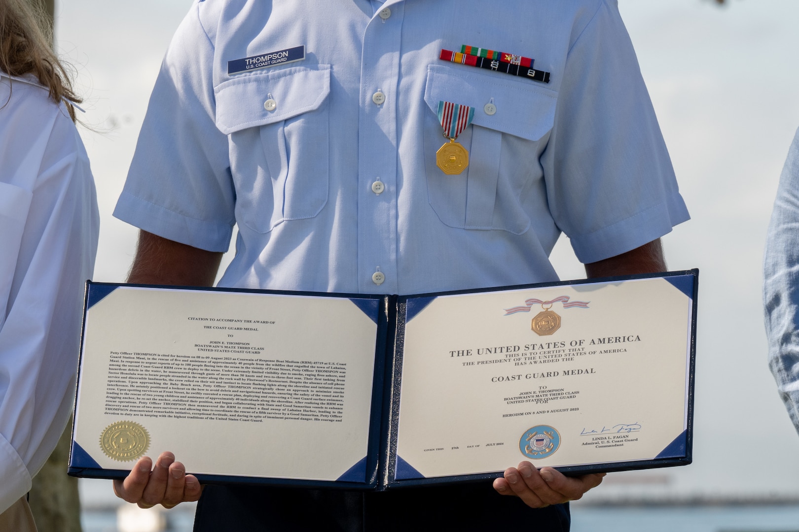 Coast Guard Petty Officer 2nd Class John Thompson holds up his award certificate.