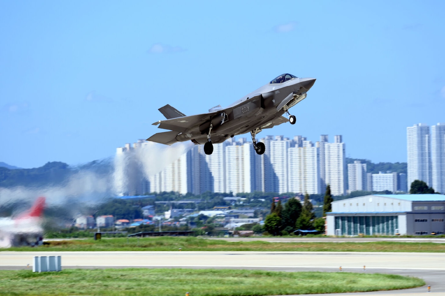 A jet takes off with skyscrapers in the background.