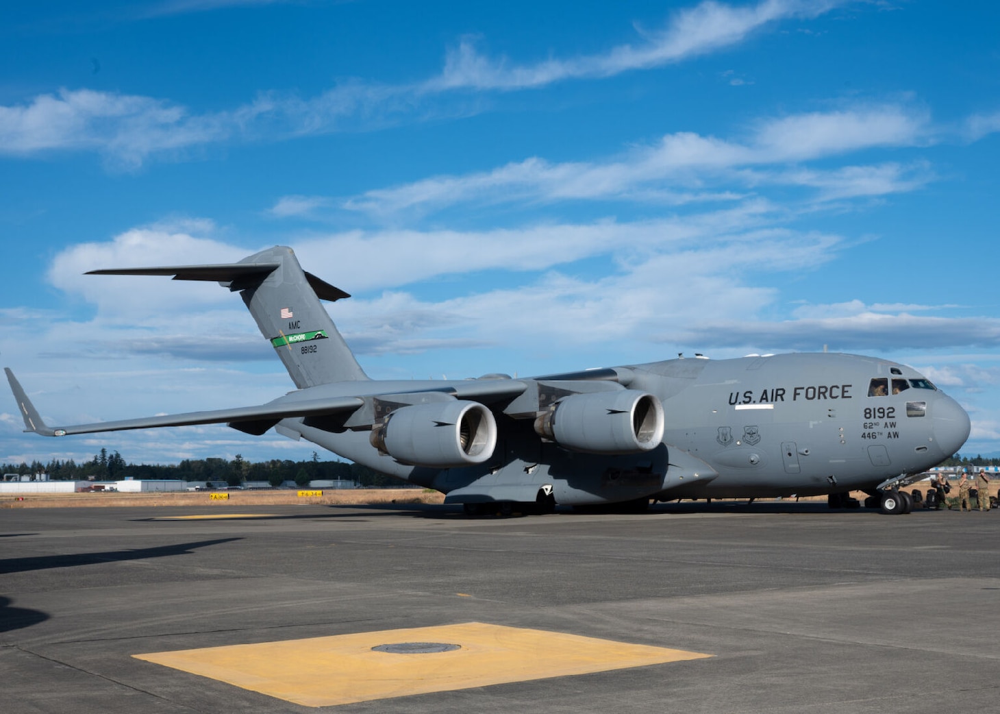 An aircraft sits on the tarmac with troops milling about.