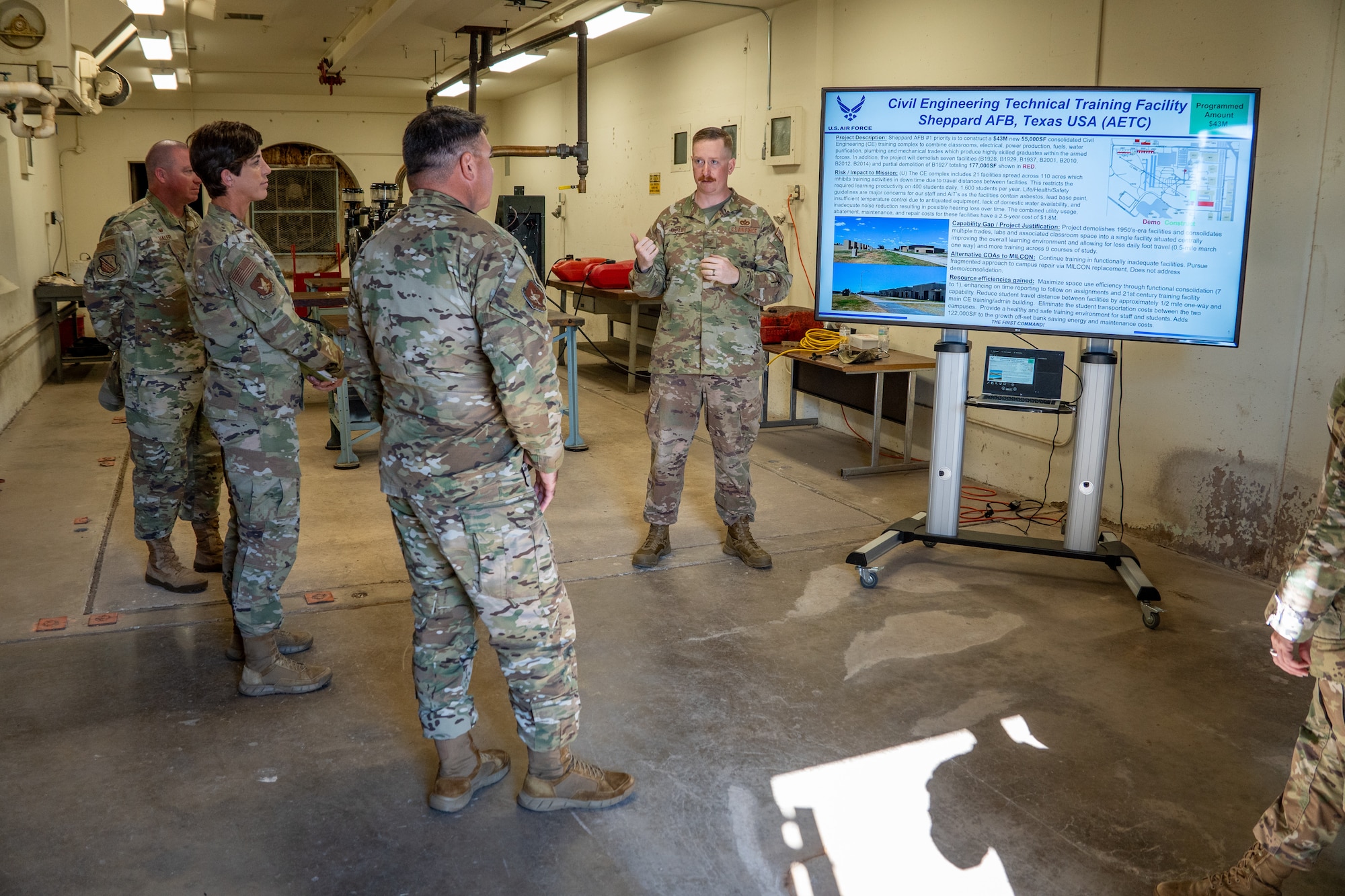 One Airman speaks to more Airman. They are looking at a monitor.