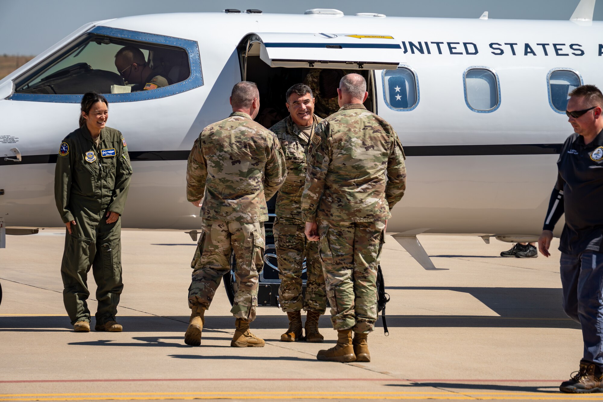 An Airmen exiting a jet is greeted by other Airmen.
