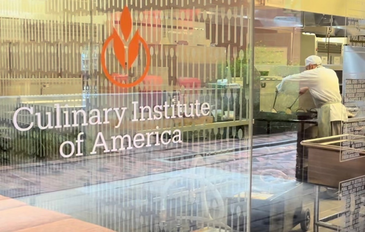 glass widow adorned with "Culinary Institute of America" with student seen through it
