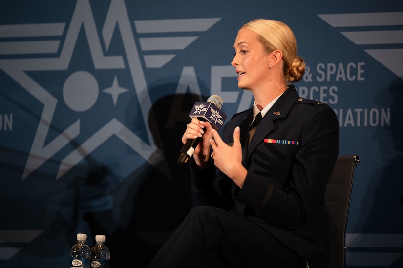 woman sits on stage and speaks into microphone