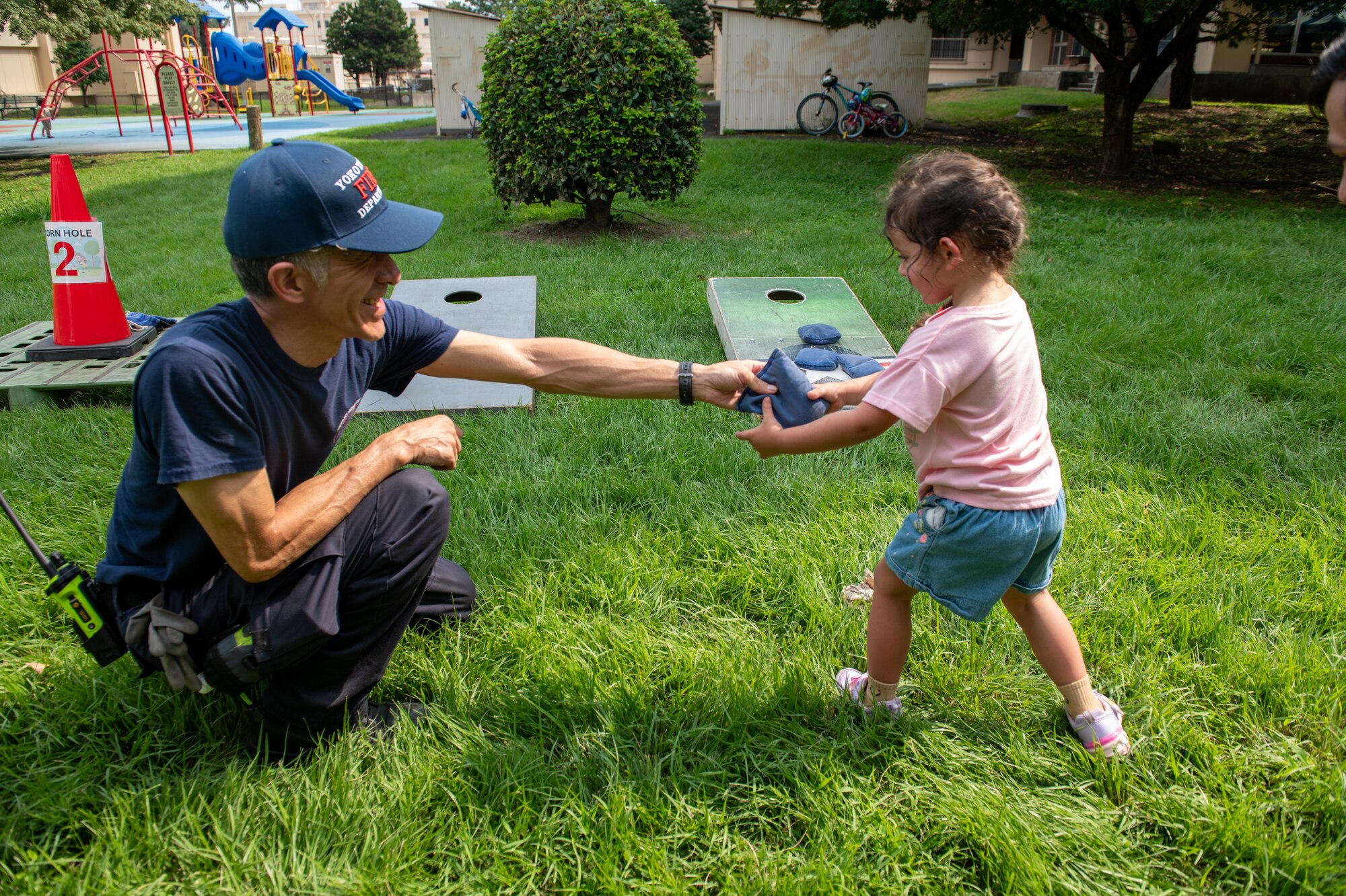 374th Civil Engineer Squadron firefighter hands a bean bag to a child during Fire prevention Week kickoff event.