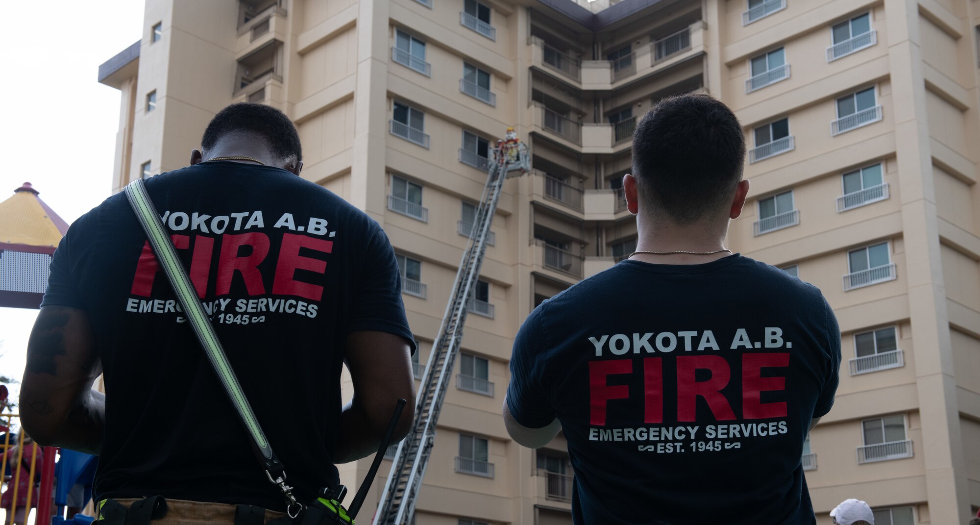 374th Civil Engineer Squadron firefighters watch the Tokyo Fire Department demonstration of saving Sparky the Fire Dog from a window.