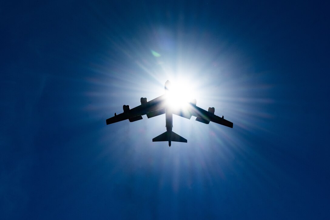 Sunlight is reflected off a large aircraft, scattering it across a deep blue sky.