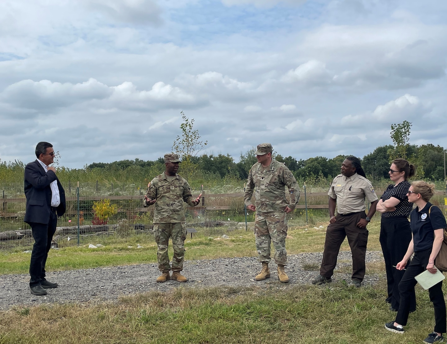 Team members gathered in a semi circle discuss a project in a field-like setting