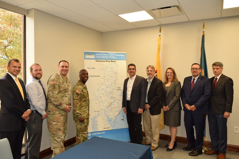Leaders gather for a group photo in front of a map of the Delaware River basin