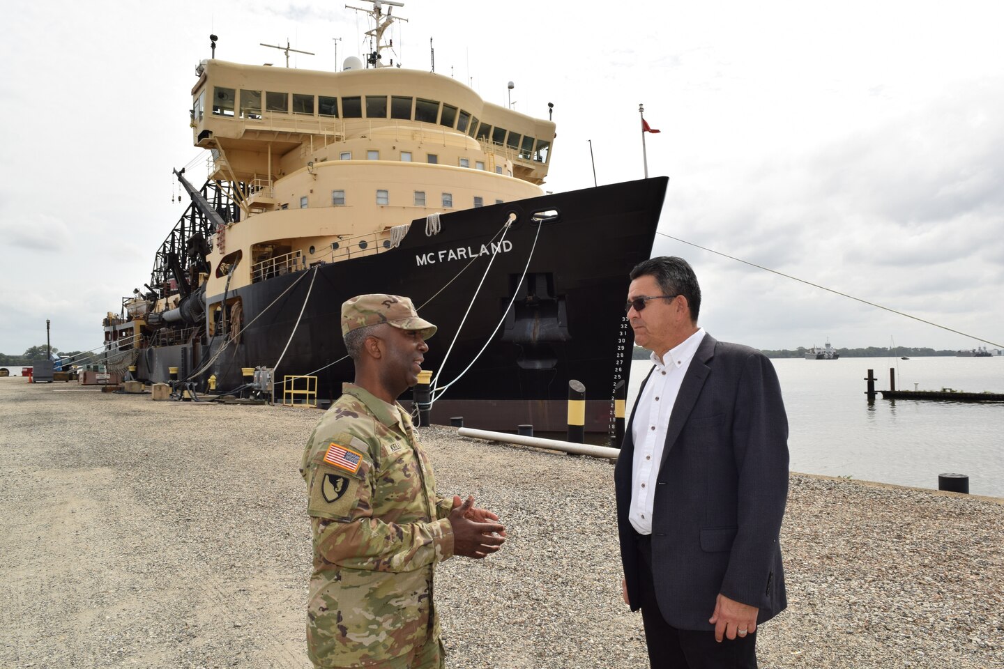 Leaders speak to each other with a dredging vessel in the background