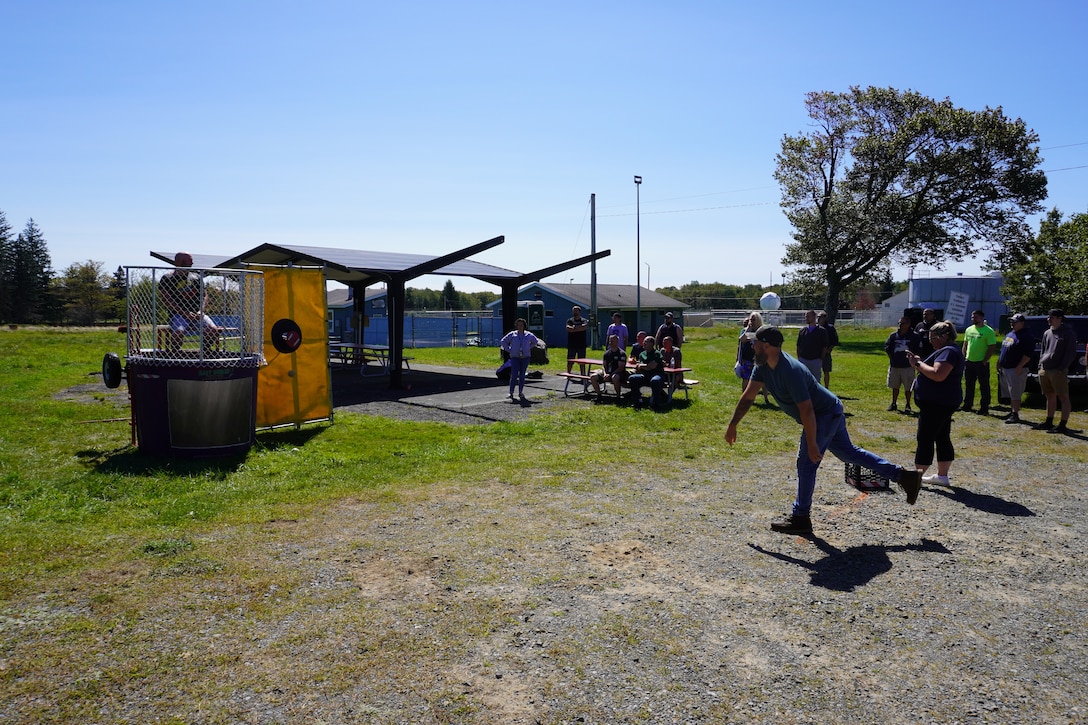 A man throws a ball at a dunk tank target.