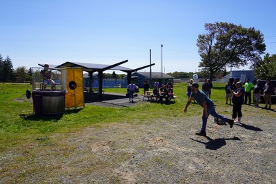 A man throws a ball at a dunk tank target.