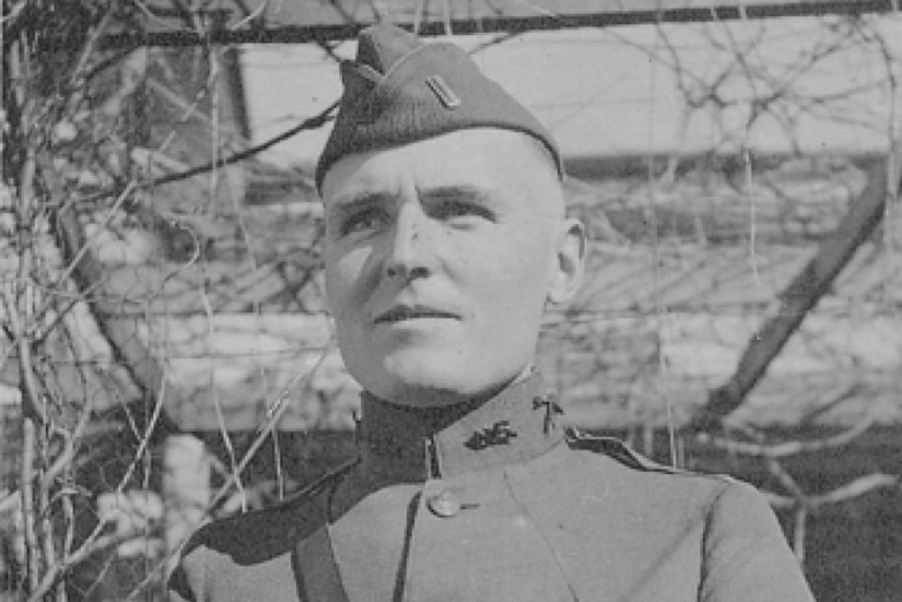 A man wearing a uniform and cap looks into the distance.