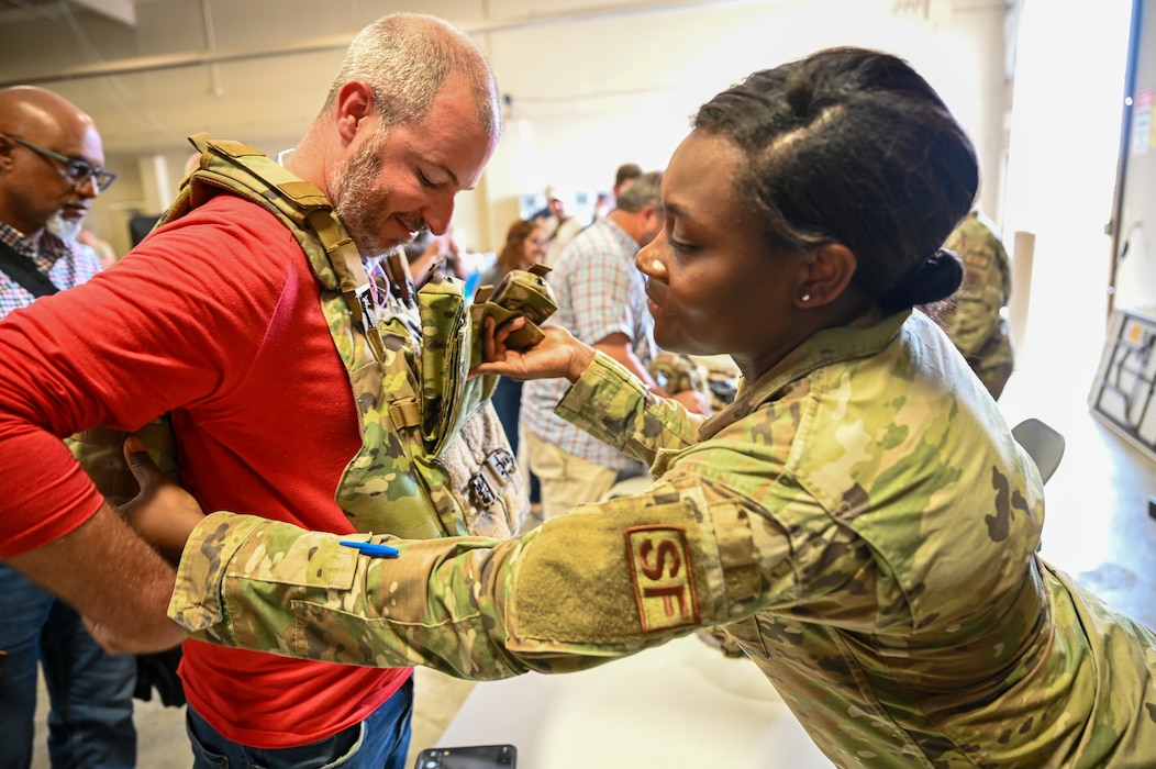 Senior Airman Deonna Brown, 433rd Security Forces Squadron defender, helps Keith Wechsler, USAA assistant vice president homeowners product leader, try on military body armor during the “Bosslift” event Sept. 14, 2024, at Joint Base San Antonio-Lackland, Texas.