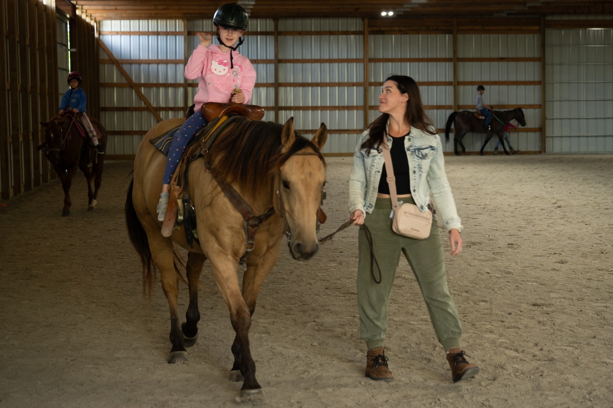 Young riders learn how to work around horses during a horsemanship class