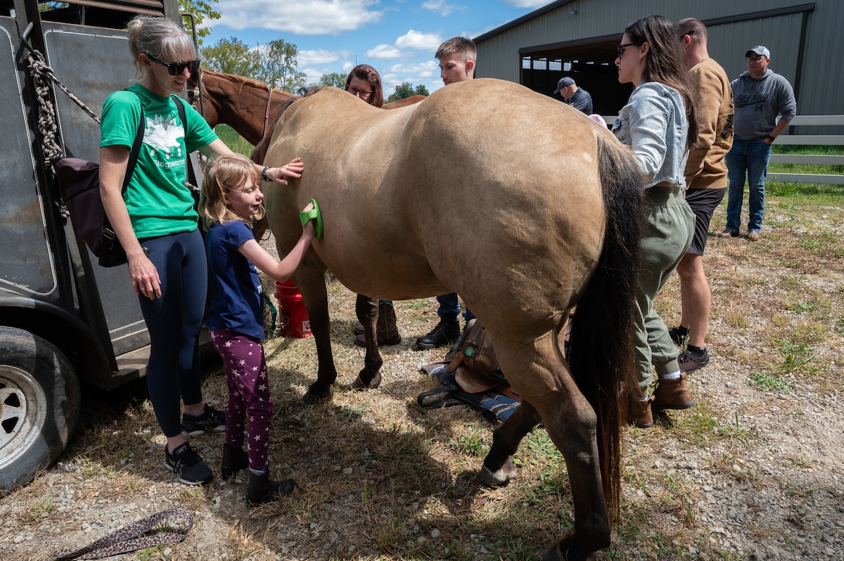 Young riders learn how to work around horses during a horsemanship class