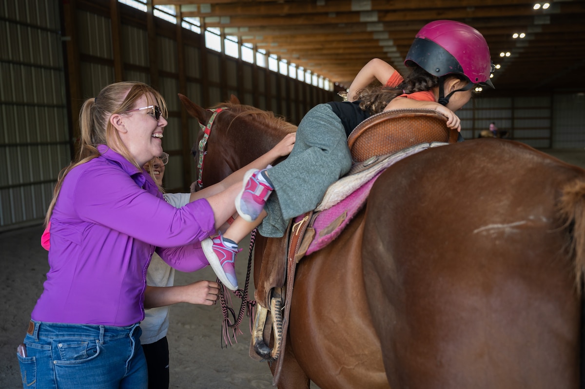 Young riders learn how to work around horses during a horsemanship class