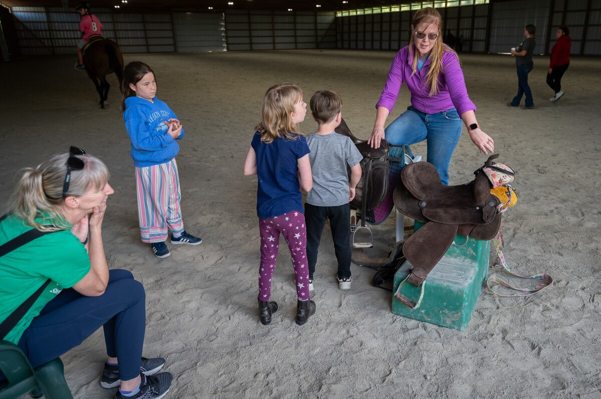 Young riders learn how to work around horses during a horsemanship class