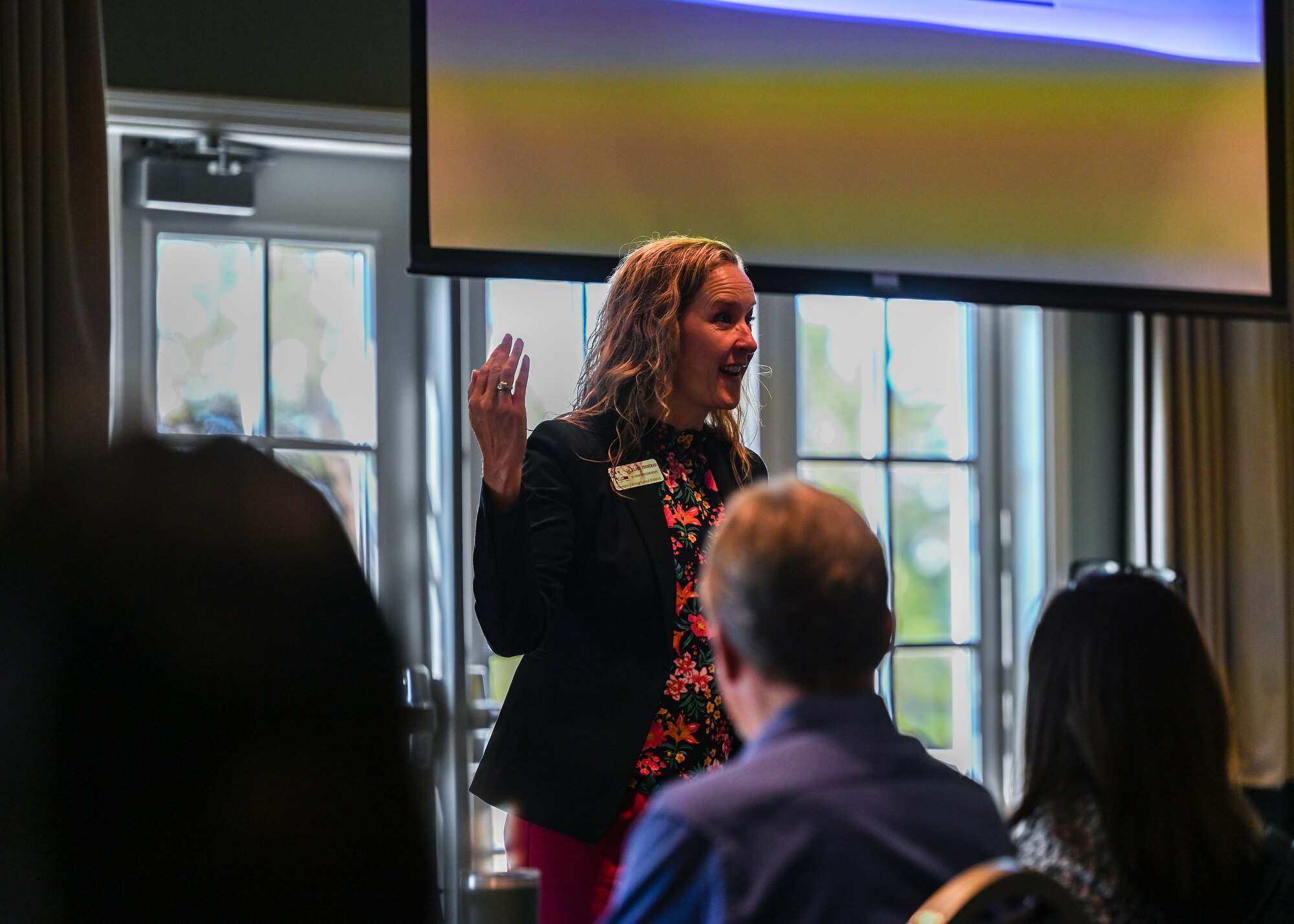 A woman speaks to attendees of a meeting.