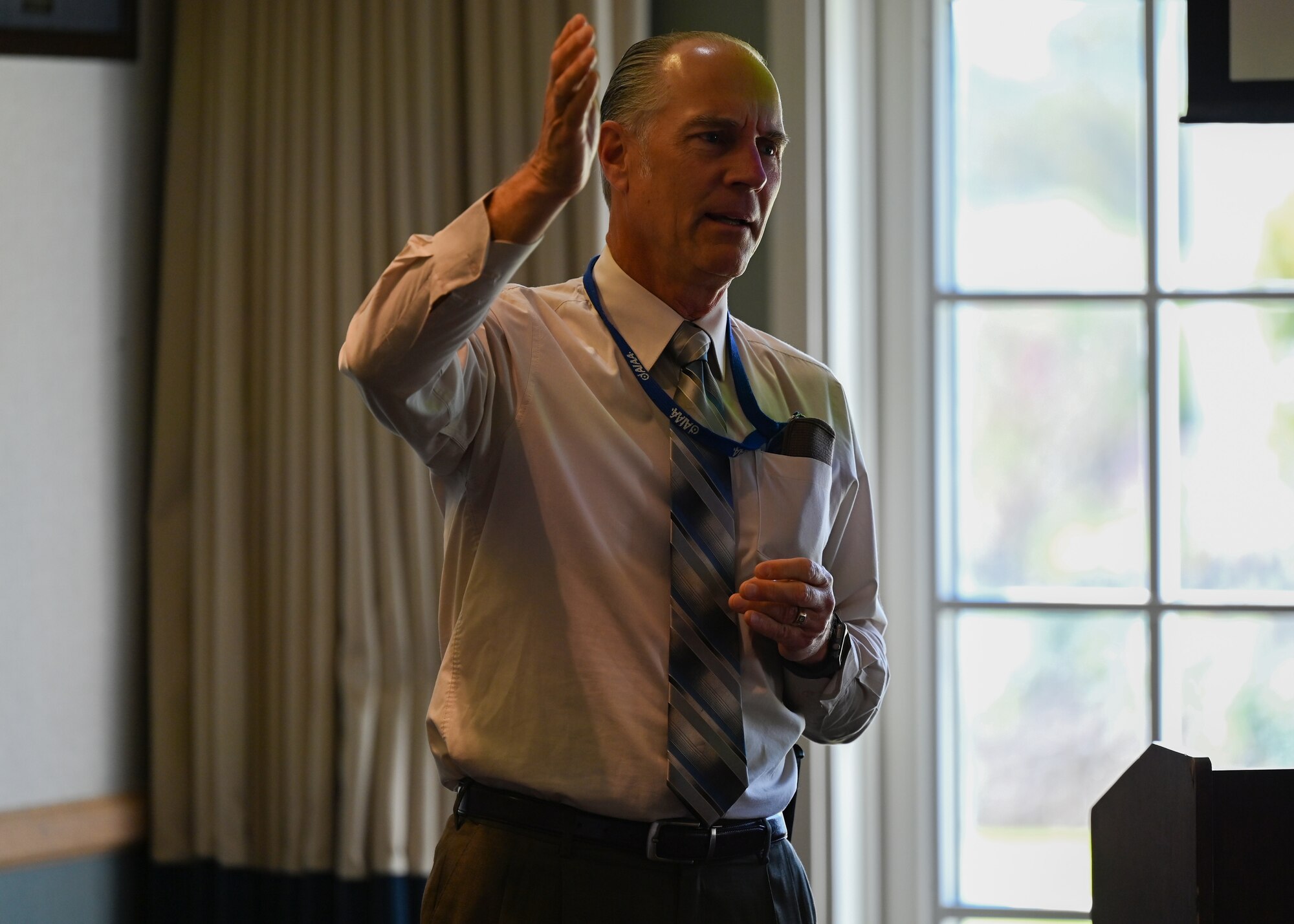 A man speaks to attendees of a meeting.