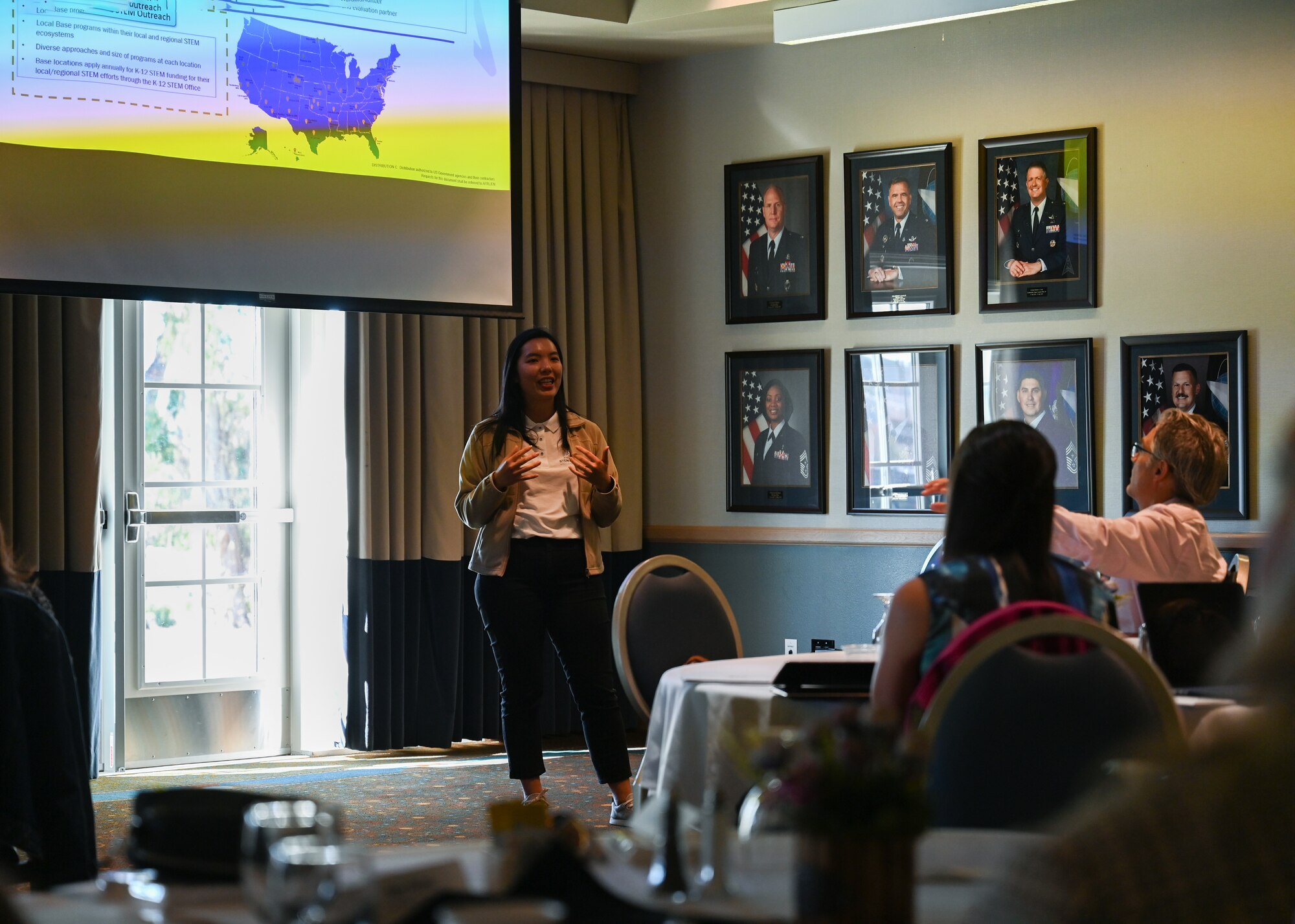 A woman speaks to attendees of a meeting.
