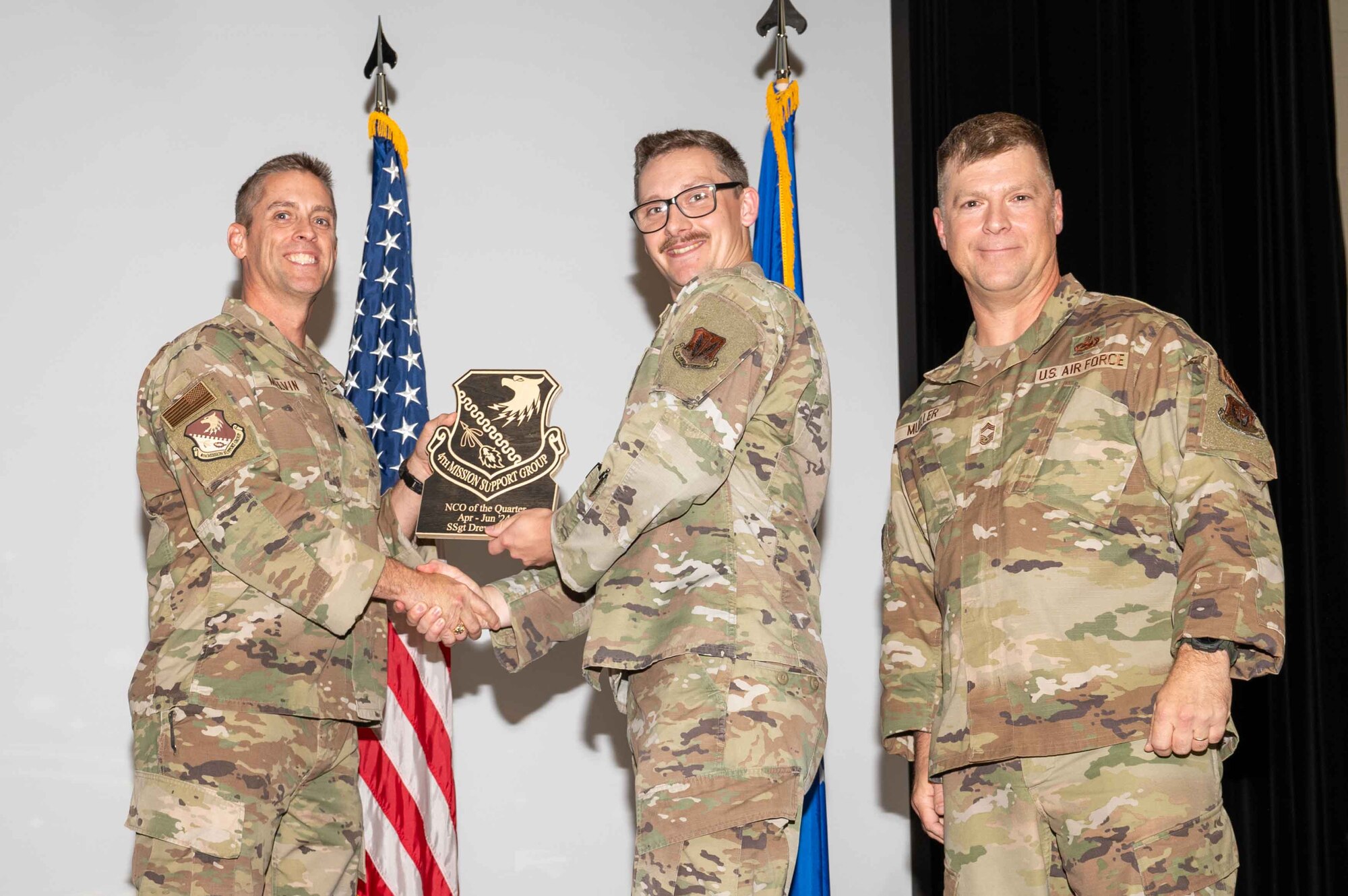 U.S. Air Force Staff Sgt. Drew Davis, center, 4th Civil Engineer Squadron structural craftsman, accepts the Non-Commissioned Officer of the 2nd Quarter Award from Col. James Melvin, left, 4th Mission Support Group deputy commander, and Chief Master Sgt.  Edward Mueller, 4 MSG senior enlisted leader, during the 4 MSG 2nd Quarter Awards ceremony at Seymour Johnson Air Force Base, North Carolina, July 26, 2024. Quarterly Awards are awarded to Airmen and civilians in different categories including civilians and Airmen of the quarter. (U.S. Air Force photo by Airman 1st Class Rebecca Tierney)