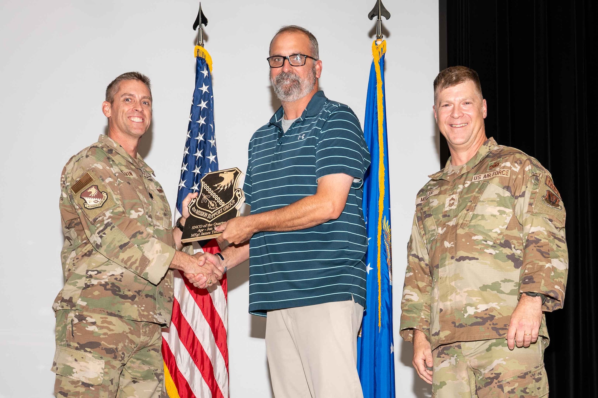 David Houtz, center, 4th Security Forces deputy commander, accepts the Senior Non-Commissioned Officer of the 2nd Quarter on behalf of Master Sgt. James Tisdale, 4 SF section chief, from Col. James Melvin, left, 4th Mission Support Group deputy commander, and Chief Master Sgt.  Edward Mueller, 4 MSG senior enlisted leader, during the 4 MSG 2nd Quarter Awards ceremony at Seymour Johnson Air Force Base, North Carolina, July 26, 2024. Quarterly Awards are awarded to Airmen and civilians in different categories including civilians and Airmen of the quarter. (U.S. Air Force photo by Airman 1st Class Rebecca Tierney)