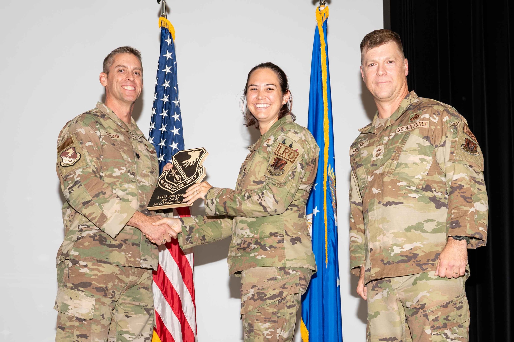 U.S. Air Force Capt. Logan Andrews, center, 4th Logistics Readiness Squadron director of operations, accepts the Junior Company Grade Officer of the 2nd Quarter on behalf of 2nd Lt Melanie Watson, 4 LRS installation deployment officer, from Col. James Melvin, left, 4th Mission Support Group deputy commander, and Chief Master Sgt.  Edward Mueller, 4 MSG senior enlisted leader, during the 4 MSG 2nd Quarter Awards ceremony at Seymour Johnson Air Force Base, North Carolina, July 26, 2024. Quarterly Awards are awarded to Airmen and civilians in different categories including civilians and Airmen of the quarter. (U.S. Air Force photo by Airman 1st Class Rebecca Tierney)