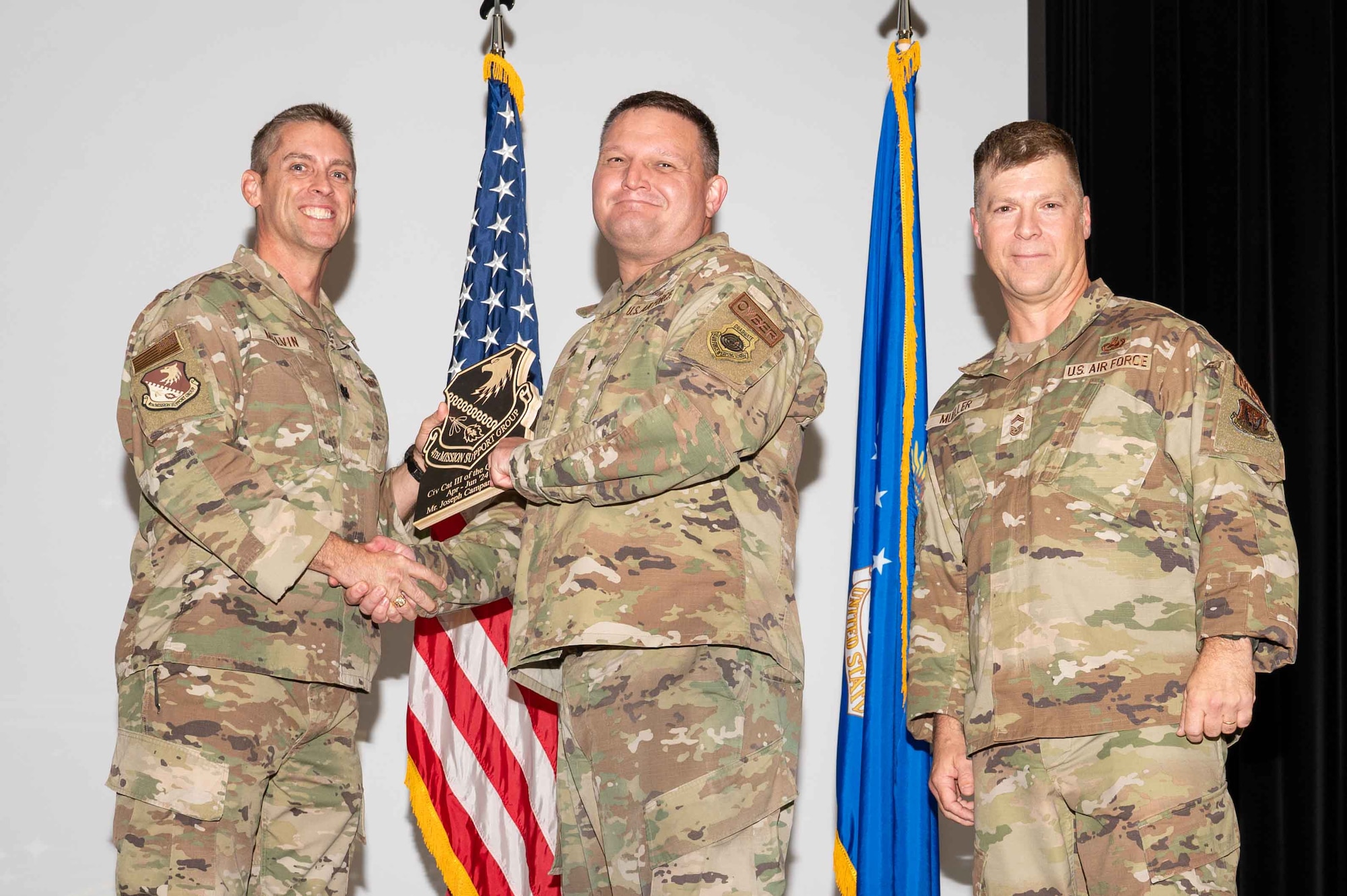 U.S. Air Force Lt. Col. Joshua Gminski, center, 4th Cyber Squadron commander, accepts the Civilian Category III of the 2nd Quarter on behalf of Joseph Campaniello, 4th Communications Squadron flight director, from Col. James Melvin, left, 4th Mission Support Group deputy commander, and Chief Master Sgt.  Edward Mueller, 4 MSG senior enlisted leader, during the 4 MSG 2nd Quarter Awards ceremony at Seymour Johnson Air Force Base, North Carolina, July 26, 2024. Quarterly Awards are awarded to Airmen and civilians in different categories including civilians and Airmen of the quarter. (U.S. Air Force photo by Airman 1st Class Rebecca Tierney)