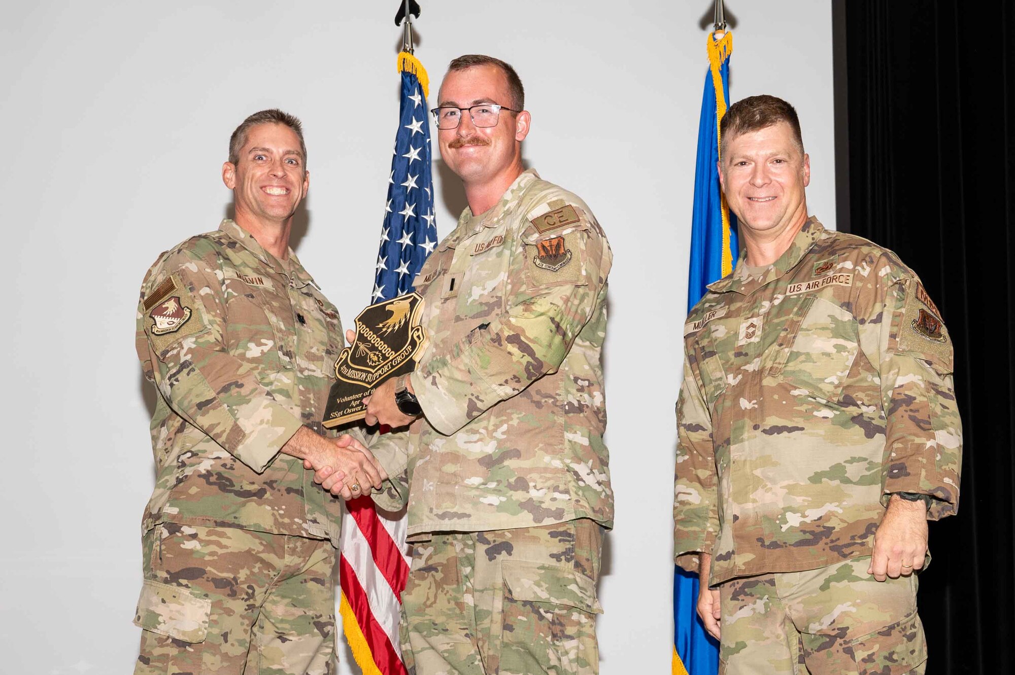 U.S. Air Force 1st Lt. Spencer Miller, 4th Civil Engineer Officer in Charge of Requirements and Optimization, accepts the Volunteer of the Quarter Award on behalf of Staff Sgt. Oswer Leiva-Benitez, 4 CE utilities Requirements and Optimization manager, from Col. James Melvin, left, 4th Mission Support Group deputy commander, and Chief Master Sgt.  Edward Mueller, 4 MSG senior enlisted leader, during the 4 MSG 2nd Quarter Awards ceremony at Seymour Johnson Air Force Base, North Carolina, July 26, 2024. Quarterly Awards are awarded to Airmen and civilians in different categories including civilians and Airmen of the quarter. (U.S. Air Force photo by Airman 1st Class Rebecca Tierney)